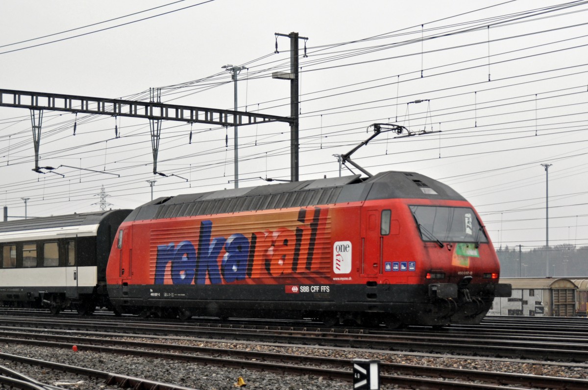 Re 460 087-0 mit der REKA Werbung durchfährt bei leichtem Schneefall den Bahnhof Muttenz. Die Aufnahme stammt vom 26.01.2015.
