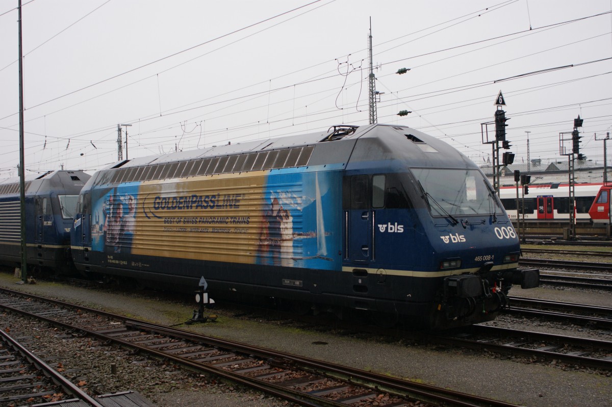 Re 465 008-1 und der Golden Passline Werbung an einem Regentag auf einem Abstellgleis am Badischen Bahnhof in Basel. Die Aufnahme stammt vom 04.01.2014.