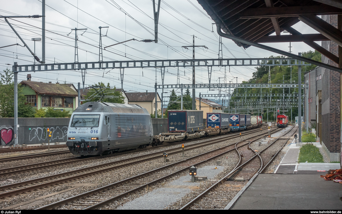 Re 465 016 mit Werbung für die Stockhornbahn durchfährt am 24. August 2018 mit einem UKV-Zug den Bahnhof Ostermundigen. Links der Lok ist hinter der Lärmschutzwand das alte Stellwerk zu erkennen.