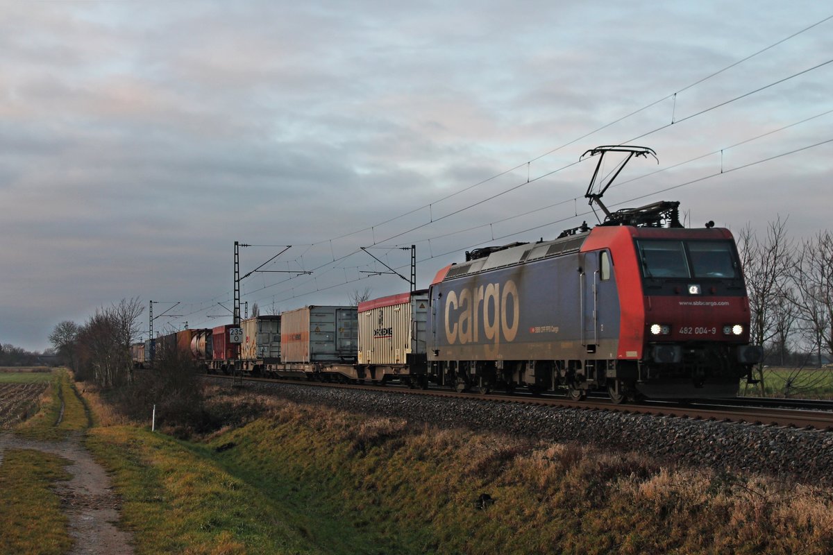 Re 482 004-9 am 23.12.2017, als sie mit einem Containerzug vor dem Sonnenaufgang bei Hügelheim durchs Rheintal in Richtung Norden fuhr.