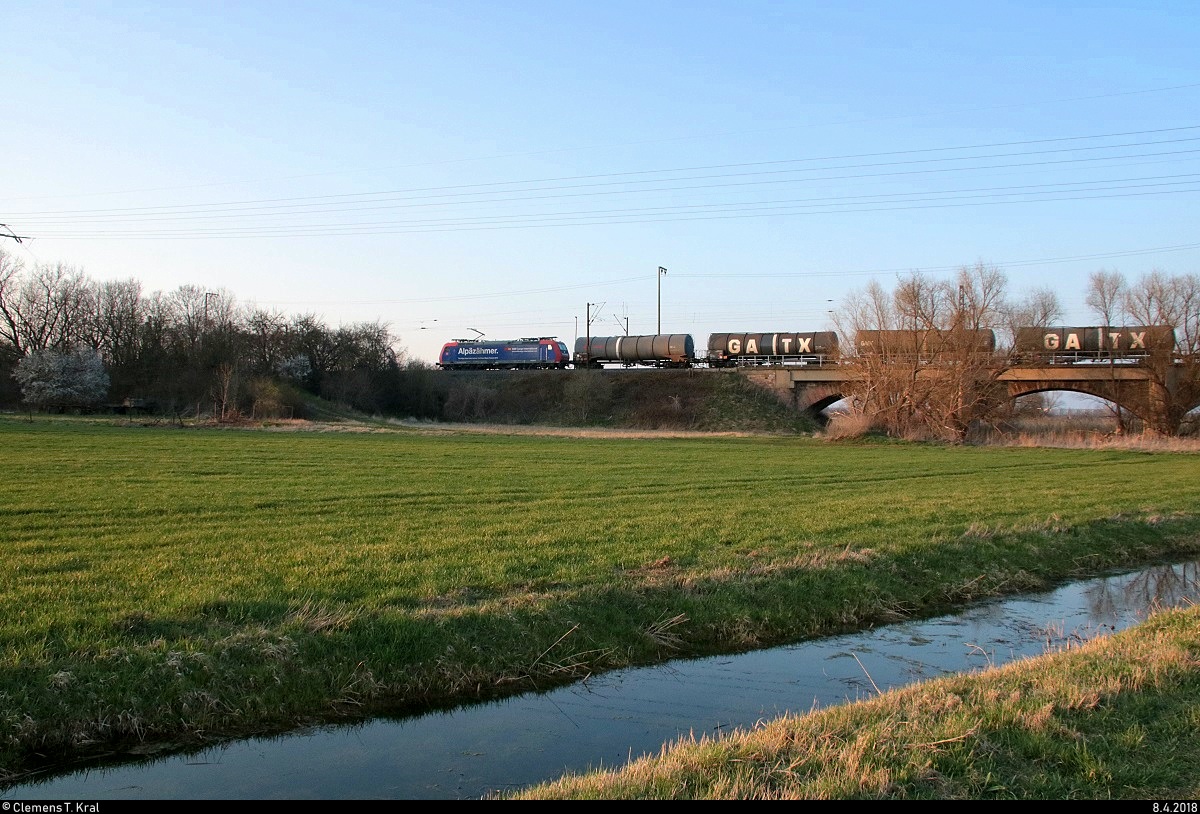 Re 482 018-9 von SBB Cargo International mit Werbung für den Gotthard-Basistunnel als Kesselzug fährt in der Saaleaue bei Angersdorf auf der Bahnstrecke Halle–Hann. Münden (KBS 590) Richtung Angersdorf. [8.4.2018 | 19:14 Uhr]