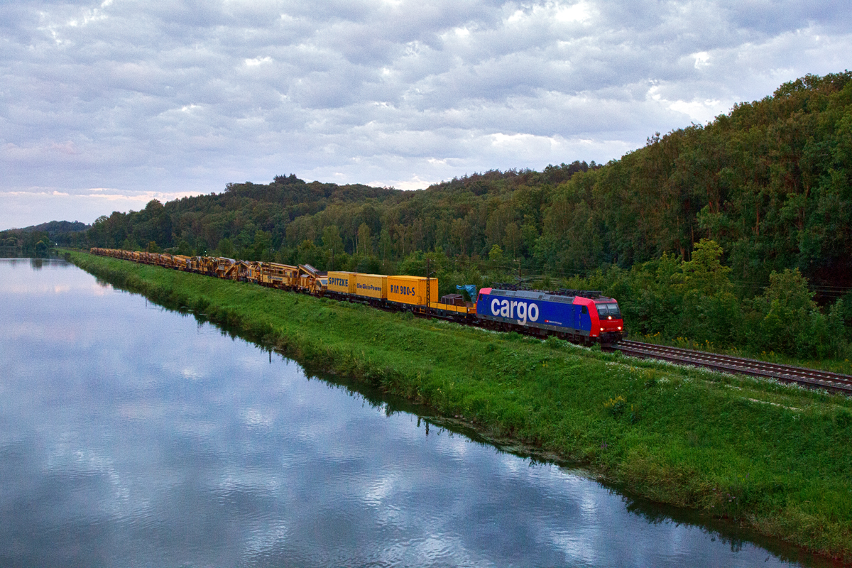 Re 482 030-4 kommt beim Einnachten bei Günzburg an der Donau entlanggefahren
mit einem Schienenbauzug.Bild vom 19.8.2014