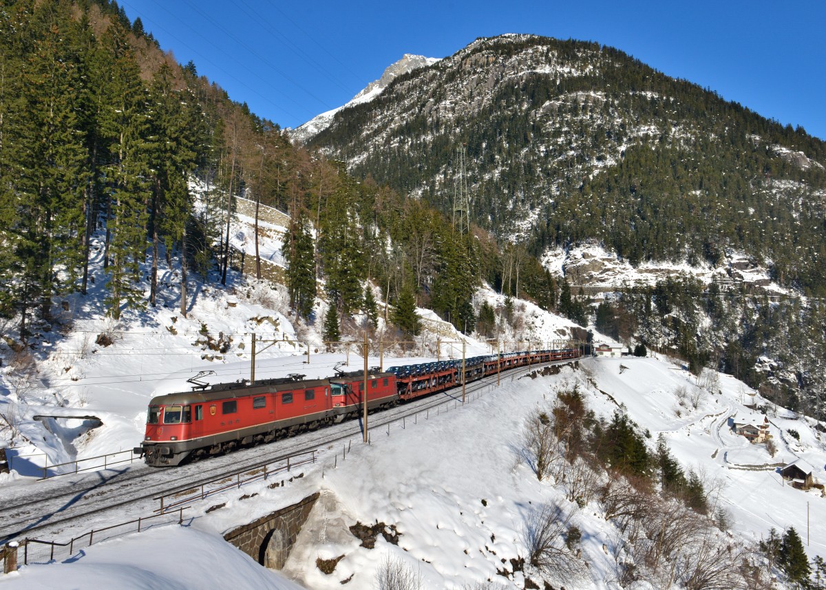Re 6/6 11601 mit einer Re 4/4 und einem Autozug am 11.02.2015 oberhalb von Wassen. 