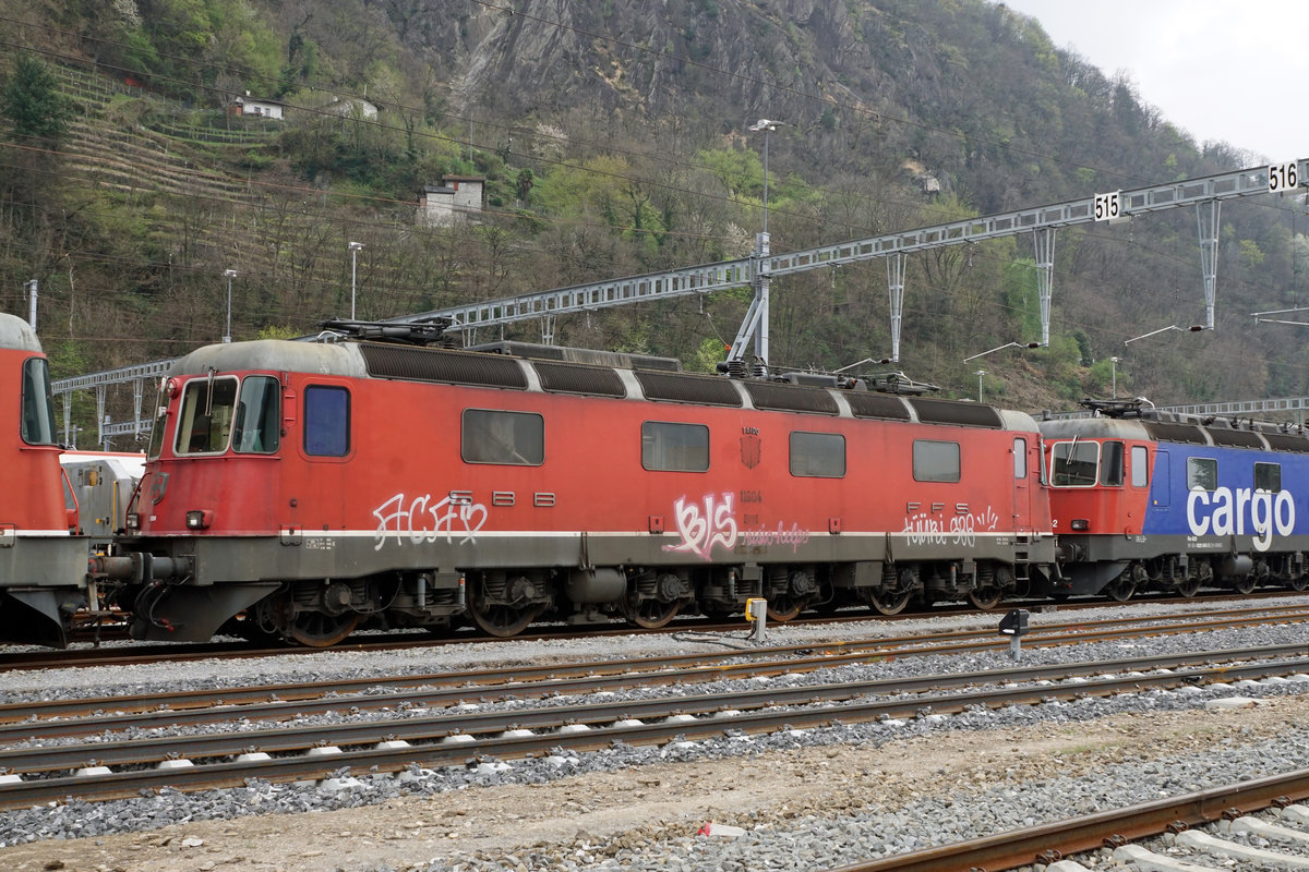 Re 6/6  Prototypen auf dem Abstellgeleise in Bellinzona-San Paolo.
Werden die Re 6/6 mit den Betriebsnummern 11601 „WOLHUSEN“ 1972, 11602 „MORGES“ 1972 sowie 11604 „FAIDO“ 1972 bald zu einem zweiten Leben erweckt oder gar verschrottet? Von der Vorserie bestehend aus den Prototypen 11601 bis 11604 hat bis anhin nur die 11603  „WÄDENSWIL“ 1972 dank RailAdventure überlebt.
Von den vier Ende 1969 bestellten Re 6/6-Lokomotiven, die wesentliche Konstruktionsprizipien  der Re 4/4 II Re 4/4 II aufweisen, wurden die beiden ersten mit geteiltem Kasten (analog RhB Ge 6/6 701-707) ausgeführt.
Beim Bau  der weiteren Re 6/6 11605 bis 11689, die in den Jahren 1975 bis 1980 in Betrieb genommen wurden, hatte man bewusst auf den geteilten  Kasten verzichtet.
Am 11. April 2019 konnten diese Raritäten in einem sehr schlechten Zustand auf einem Bild verewigt werden.
Geschieht nicht doch noch bald ein Wunder, handelt es sich um meine letzten Aufnahmen dieser sehr speziellen Lokomotiven der schweizerischen Bahngeschichte.
Fotostandort zugängliche Wiese, Bildausschnitt Fotoshop.
Foto: Walter Ruetsch    
