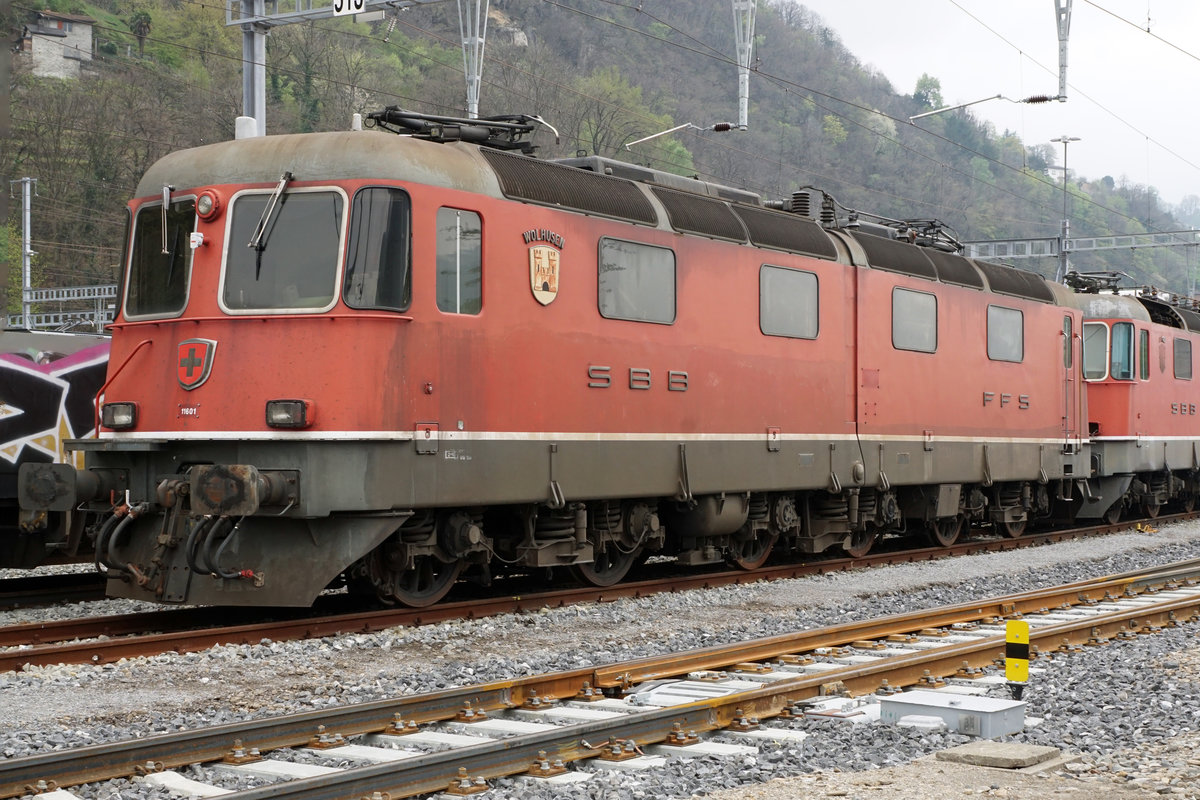 Re 6/6  Prototypen auf dem Abstellgeleise in Bellinzona-San Paolo.
Werden die Re 6/6 mit den Betriebsnummern 11601 „WOLHUSEN“ 1972, 11602 „MORGES“ 1972 sowie 11604 „FAIDO“ 1972 bald zu einem zweiten Leben erweckt oder gar verschrottet? Von der Vorserie bestehend aus den Prototypen 11601 bis 11604 hat bis anhin nur die 11603  „WÄDENSWIL“ 1972 dank RailAdventure überlebt.
Von den vier Ende 1969 bestellten Re 6/6-Lokomotiven, die wesentliche Konstruktionsprizipien  der Re 4/4 II Re 4/4 II aufweisen, wurden die beiden ersten mit geteiltem Kasten (analog RhB Ge 6/6 701-707) ausgeführt.
Beim Bau  der weiteren Re 6/6 11605 bis 11689, die in den Jahren 1975 bis 1980 in Betrieb genommen wurden, hatte man bewusst auf den geteilten  Kasten verzichtet.
Am 11. April 2019 konnten diese Raritäten in einem sehr schlechten Zustand auf einem Bild verewigt werden.
Geschieht nicht doch noch bald ein Wunder, handelt es sich um meine letzten Aufnahmen dieser sehr speziellen Lokomotiven der schweizerischen Bahngeschichte.
Fotostandort zugängliche Wiese, Bildausschnitt Fotoshop.
Foto: Walter Ruetsch    
