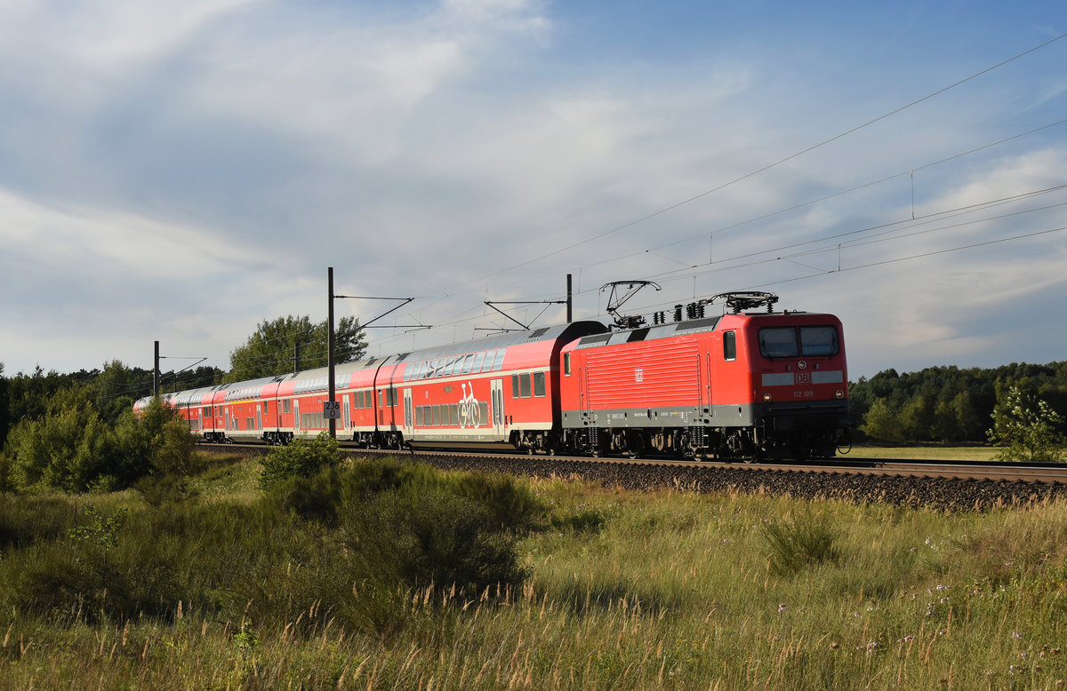 RE1 des Hanse-Express mit der 112 109-4 in Front. Kurz nach der Abfahrt vom Bahnhof Büchen, kommend aus Hamburg. 3km östlich von Büchen, 06.08.2018.