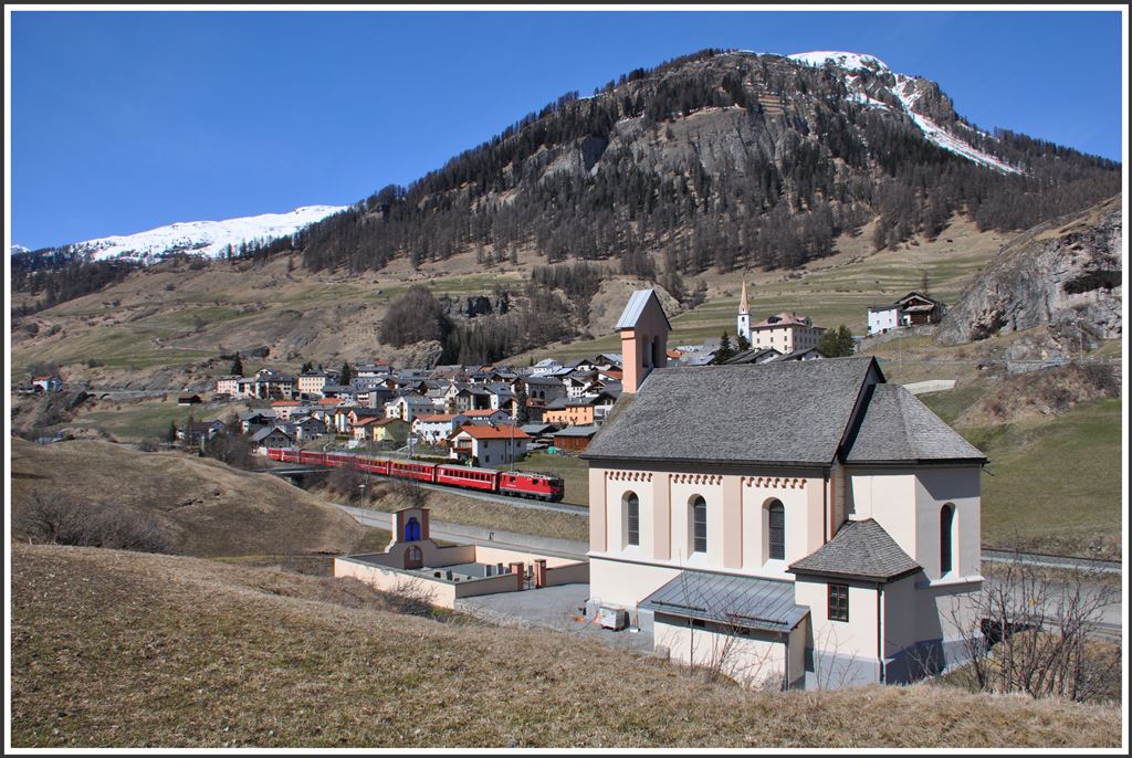 RE1241 mit der Ge 4/4 II 614  Schiers  passiert die katholische Kirche am Dorfrand von Ardez. (09.04.2015)