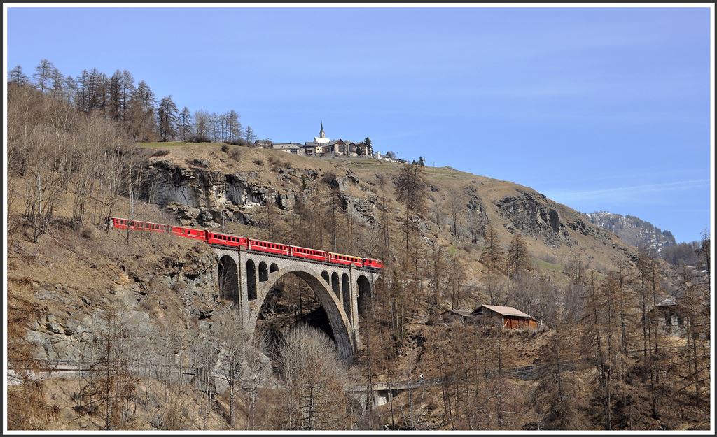 RE1342 mit der Ge 4/4 II 631  Untervaz  in Giarsun auf der grossen Bogenbrücke über die Clozza. In wenigen Aufenblicke wird der Bahnhof von Guarda erreicht. Das Dorf liegt 250m höher auf einer Sonnenterrasse. (10.04.2015)