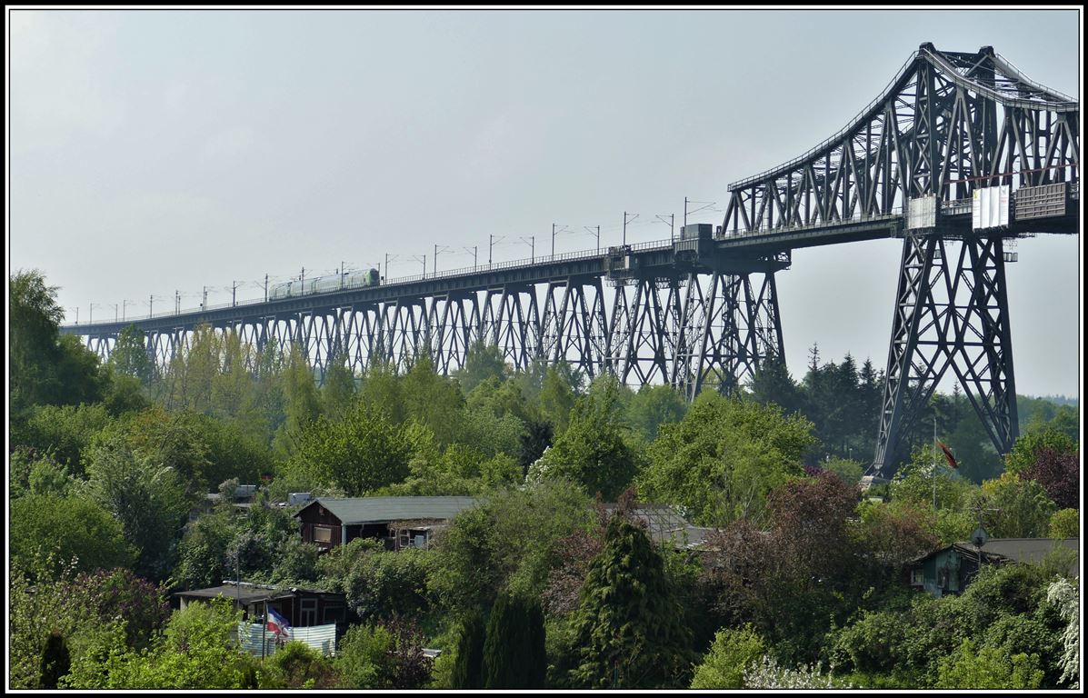 RE21060 aus Hamburg mit einer Doppelstockgarnitur BR445 nähert sich dem Mittelteil der 2170m langen Rendsburger Hochbrücke über den Nord-Ostsee-Kanal.Aufnahmeort Sundawitter Weg. (18.05.2019)