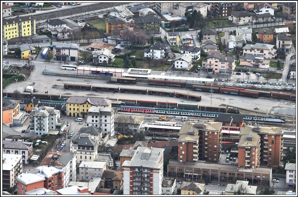 Reg 2560 aus Milano ist in Tirano eingetroffen. Schublok Trenord ist eine E464. Die Güterwagen auf dem Freiverladeplatz verlassen Tirano täglich mit Ganzzügen, gefüllt mit Mineralwasser. Zu sehen sind hier das italienische Normalspurbahnhofgebäude und rechts davon das niedere Gebäude des RhB Bahnhofs. Hinter den Geleisen befindet sich der Busbahnhof Richtung Bormio,Aprica/Edolo, Lugano und Poschiavo. (21.02.2014)