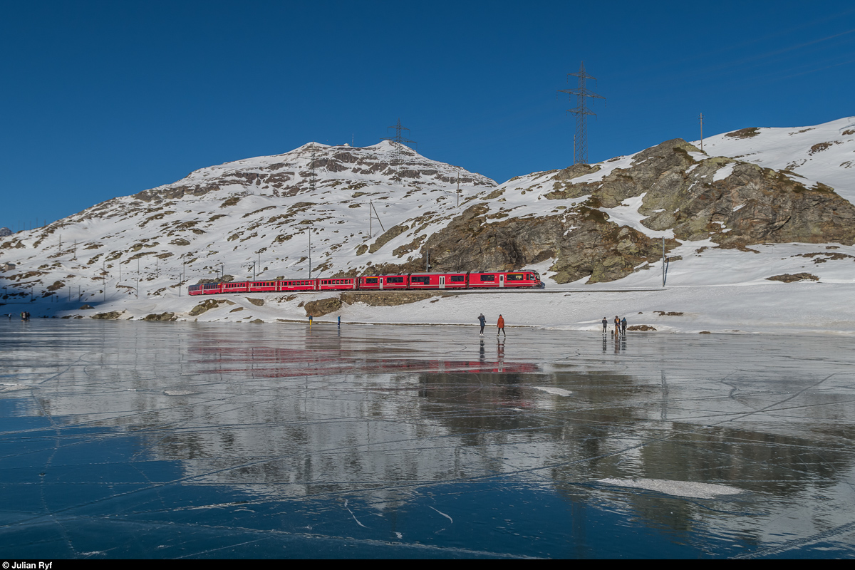 Regio 1633 St. Moritz - Tirano fährt am 29. Dezember 2016 am mit Schwarzeis bedeckten Lago Bianco entlang.