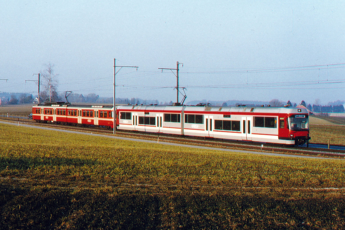 Regionalverkehr Bern-Solothurn/RBS.
Die bunten Züge der 1990er-Jahre.
S-Bahn  8 zwischen Jegenstorf und Urtenen mit Be 4/8 62  ITTIGEN und Be 4/8 MANDARINLI.
Die Be 4/8 62-64 PRIMA waren für den Vorortsverkehr bestimmt und hatten daher keine 1. Klasse bis zum Einbau des Zwischenwagens ca. 2001.
Wegen den hohen Passagierzahlen kam es auch bei den MANDARINLI zum Einbau von Zwischenwagen mit Niederflureinstieg.
Foto: Walter Ruetsch