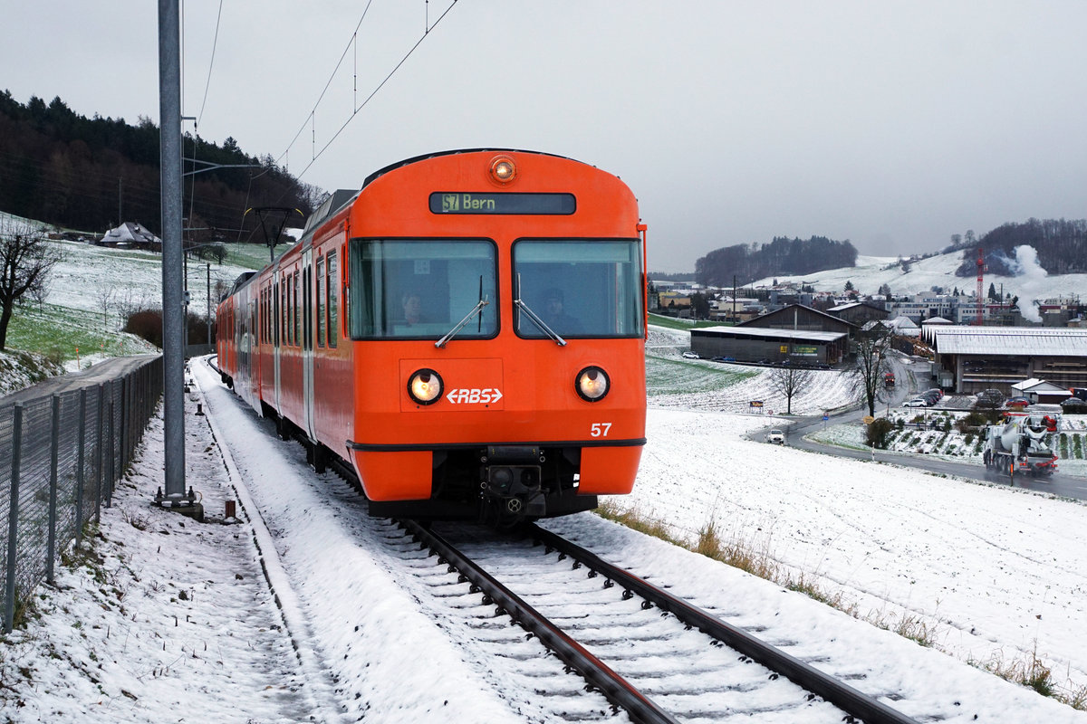 Regionalverkehr Bern Solothurn/RBS.
MANDARINLI  ADIEU.
Nach 45 Dienstjahren haben die bekannten Mandarinli, wie sie im Volksmund heissen ausgedient.
Während diesen vielen Jahren prägten sie das Bild sehr stark im Worblental auf der S 7 Bern – Worb Dorf. In der Woche vom  11. Bis zum 15. Dezember 2019 standen sie ein letztes Mal im Plandienst, damit sich die Fahrgäste und die Eisenbahnfreunde von ihnen verabschieden konnten.  Die beiden letzten Triebzüge Be 4/12 56 und Be 4/12 57 werden zwar vorerst nicht verschrottet, da sie noch als eiserne Reserve zurückbehalten werden. Da ich zusammen mit diesen eleganten orangen Triebzügen  den grössten Teil  meines Lebens verbringen  konnte, freue ich mich über sehr viele Abschiedsbilder unter BB.de.  Ich werde meinen Beitrag leisten. Ich verabschiedete mich am Freitag den 13. Dezember 2019 zusammmen mit mehreren Bahnfreunden.  
So himmeltraurig das Wetter, so traurig der Abschied von diesem Zug.  Nicht nur das Taschentuch sondern auch meine Kleider waren durch und durch nass.
Mandarinli adieu!
Foto: Walter Ruetsch

