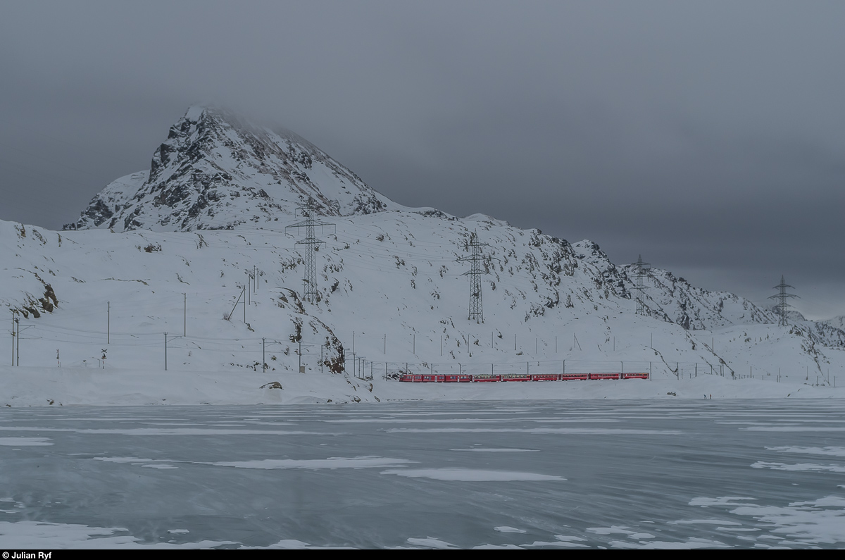 Regionalzug 1644 aus Tirano fährt am 20. Dezember 2016 kurz vor Ospizio Bernina dem Ufer des gefrorenen Lago Bianco entlang in Richtung St. Moritz.
