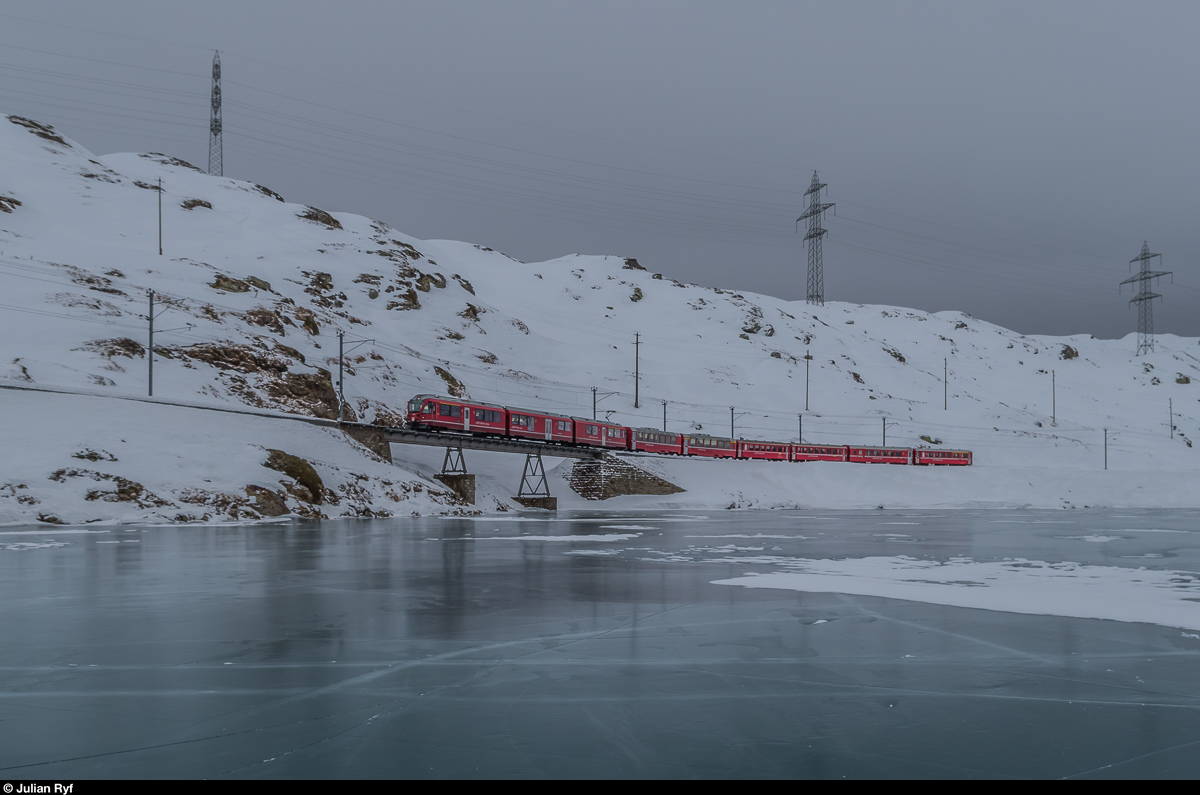 Regionalzug 1644 aus Tirano fährt am 20. Dezember 2016 kurz vor Ospizio Bernina dem Ufer des gefrorenen Lago Bianco entlang in Richtung St. Moritz.
