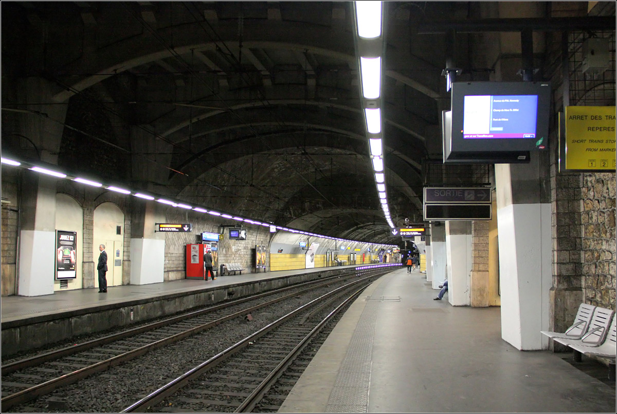 RER-Station Boulainvilliers in Paris -

Die Station liegt zwischen zwei Tunnelabschnitten. Ich bin mir nicht sicher ob schon bei der ursprünglichen Station die Bahnsteige auf der Nordseite etwas in den Tunnel reichten,oder ob beim Umbau zur RER-Station in den 1980iger Jahren die Bahnsteige in den Tunnel verlängert wurden. Ein weitere Möglichkeit wäre, dass der nördliche Teil der Bahnsteige in anderer Konstruktion zugedeckt wurden. Auf jeden Fall ändert sich nach hinten der Querschnitt.

22.07.2012 (M)