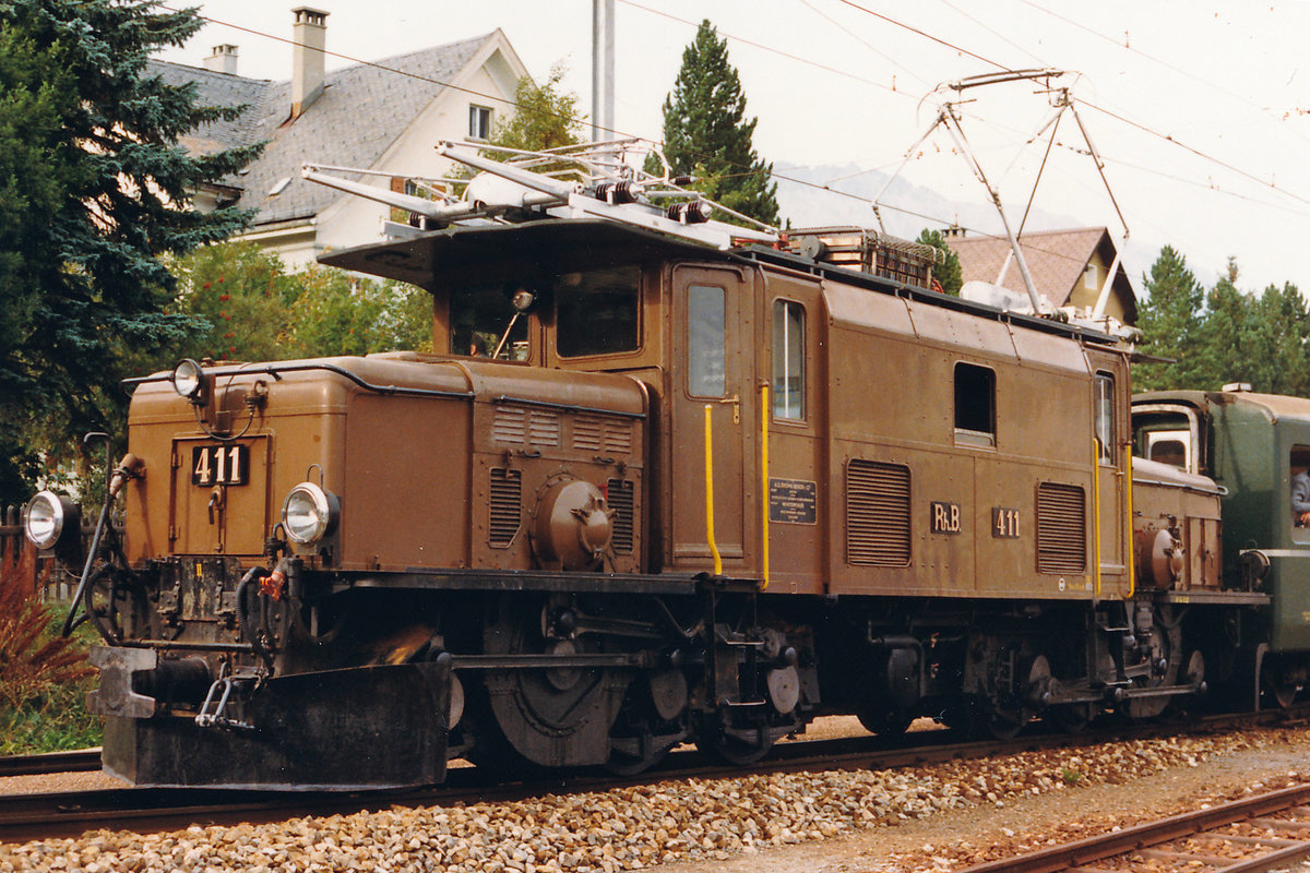 RhB: Ge 6/6 I 411 mit ihrem Güterzug mit Personenbeförderung bei einem Zwischenhalt in Bever im Oktober 1987.
Foto: Walter Ruetsch 