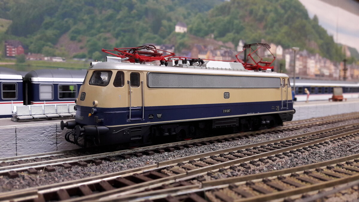 Rheingold Lokomotiven , als E10 Kasten und Bügelfalten E10 ( später 112)….
Die geplante E10 Bügelfalte war noch nicht fertig gestellt, da wurden einige E10 Kasten in Rheingoldlackierung als Provisorium umgebaut….. Provisorium 1 :  6 Loks ( 239-244) mit Getriebumbau auf 160 km/h , sie bekamen eine 1 vor der Ordnungsnummer also E10 1239 -1244 . Die 1244 bekam ein sogenanntes Henschel – Drehgestell was sie auch behielt.
Da die E10 Bügelfalte immer noch nicht fertig war, orderte man nochmal 5 Loks der Kasten E10 nach ( Provisorium 2 )  , welche direkt mit Henscheldrehgestellen ausgeliefert wurden.  E10 250-254 . Diese bekamen keine 1 davor, also wie gehabt E10 250-254 …. Zu unterscheiden waren Provisorium 1 und 2 unter anderem auch an der Beschriftung. Provisorium 1 hatte vorne den DB Keks und an der Seite keinen.  Provisorium 2 umgekehrt, vorne kein Keks, dafür an Seite. …. Ab 1962 gab es dann die ersten Bügelfalten E10 in Rheingoldausführung.  6 Loks  E10 1239-1270, diese hatten keine Rehling vorne .  Ab 1963 dann die nächste Lieferung E10 1308-1012  welche nun aber eine Rehling vorne hatten. Ab 1966 wurden die blau/ elfenbein lackierten Loks in TEE Farben umlackiert. Deswegen gab es auch mit E10  1308  usw , beschriftete E10er Bügelfalten in TEE Farben….1968 gab es dann die 3. Lieferung von 20 Loks  E10 485-504 welche aber direkt als 112 er Loks in TEE Farben ausgeliefert wurden. Alle Kasten Rheingold E10 wurden später wieder in blau zurück lackiert.  Hier das Modell der ersten Serie, Bügelfalten E10, E10 1267, Regenrinne, keine Rehling vorne, Pufferverkleidung,  Modell Roco 63704  DC digital