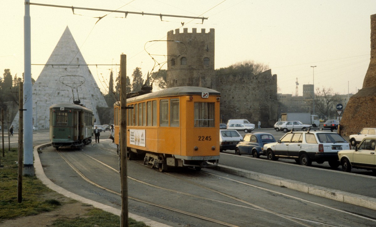 Roma / Rom ATAC SL 30/ Piazza Ostiense im Februar 1989. - Die kleine Pyramide links im Hintergrund ist die Sestius-Pyramide, die zwischen 18 und 12 v. Chr. als Grabmal errichtet wurde. - Das Gebäude rechts von der Pyramide ist die Porta San Paolo, deren Stadtseite aus der aurelianischen Zeit (270-282 n. Chr.) stammt. Die Westfront wurde am Anfang des 5. Jahrhunderts neu gestaltet.