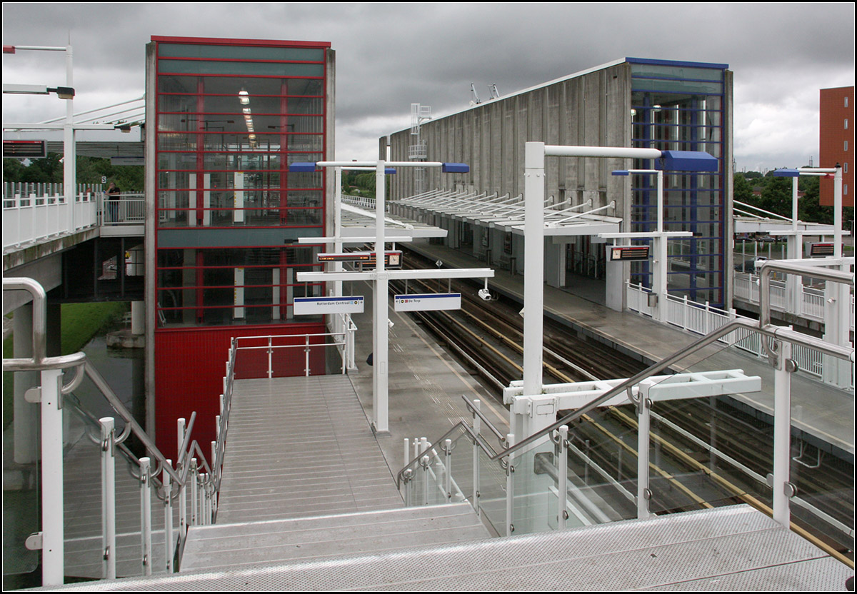 Rot und Blau -

... sind die jeweiligen Kennfarben der Rotterdamer Metrolinien. In der Station Tussenwater fädelt die Calandlijn (rot) in die Erasmuslijn (blau) ein. Diese Station wurde dabei viergleisig ausgebaut, die Calandlijn befährt die Außengleise. In Fahrtrichtung befindet sich das südliche Gleis der Caldlijn für die Fahrtrichtung Pernis dabei noch ein Stockwerk über den drei anderen Gleisen, da auf der Ostseite der Station die beiden Gleise der anderen Linie überquert werden.

21.06.2016 (M)