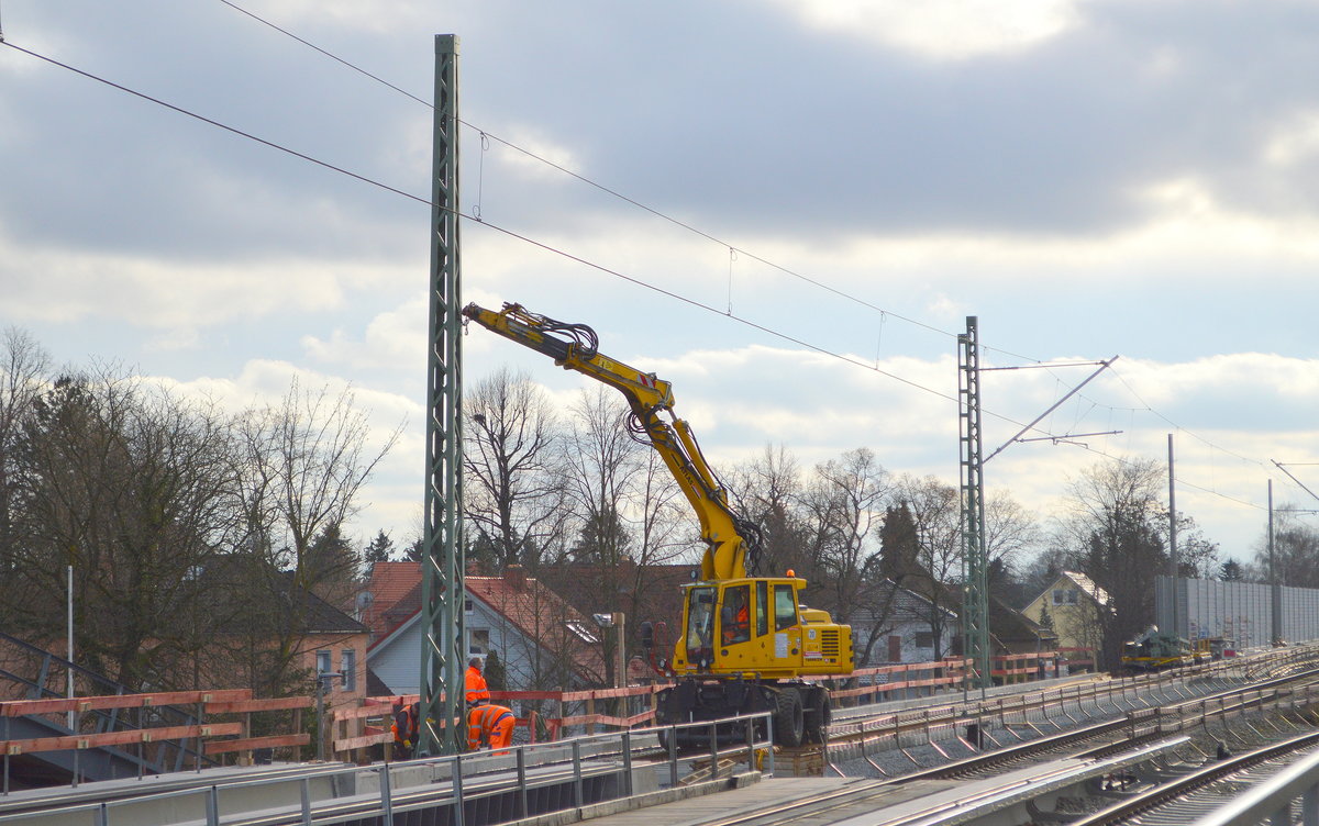 Rund um das Karower Kreuz Berlin sind nun schon über ein Jahr umfangreiche Um- und Neubauten der Bahnstrecken im Gange und ganz langsam ist Licht am Ende des Tunnels, nachdem vor einer Woche endlich die letzte fehlende Teilbrücke direkt am Bahnhof Berlin Karow eingesetzt wurde kann nun endlich der Gleisuntergrund und die Schienen langsam verlegt werden, vorab wurden schon einige Hochmasten gesetzt auf dem völlig neu gebauten Betonrand des Bahndamms, etwa dort wo einst das  Stellwerk stand das abgerissen wurde, dazu war ein Zweiwegebagger ATLAS 1604 KZW der DB Bahnbau Gruppe im Einsatz am 28.01.21 