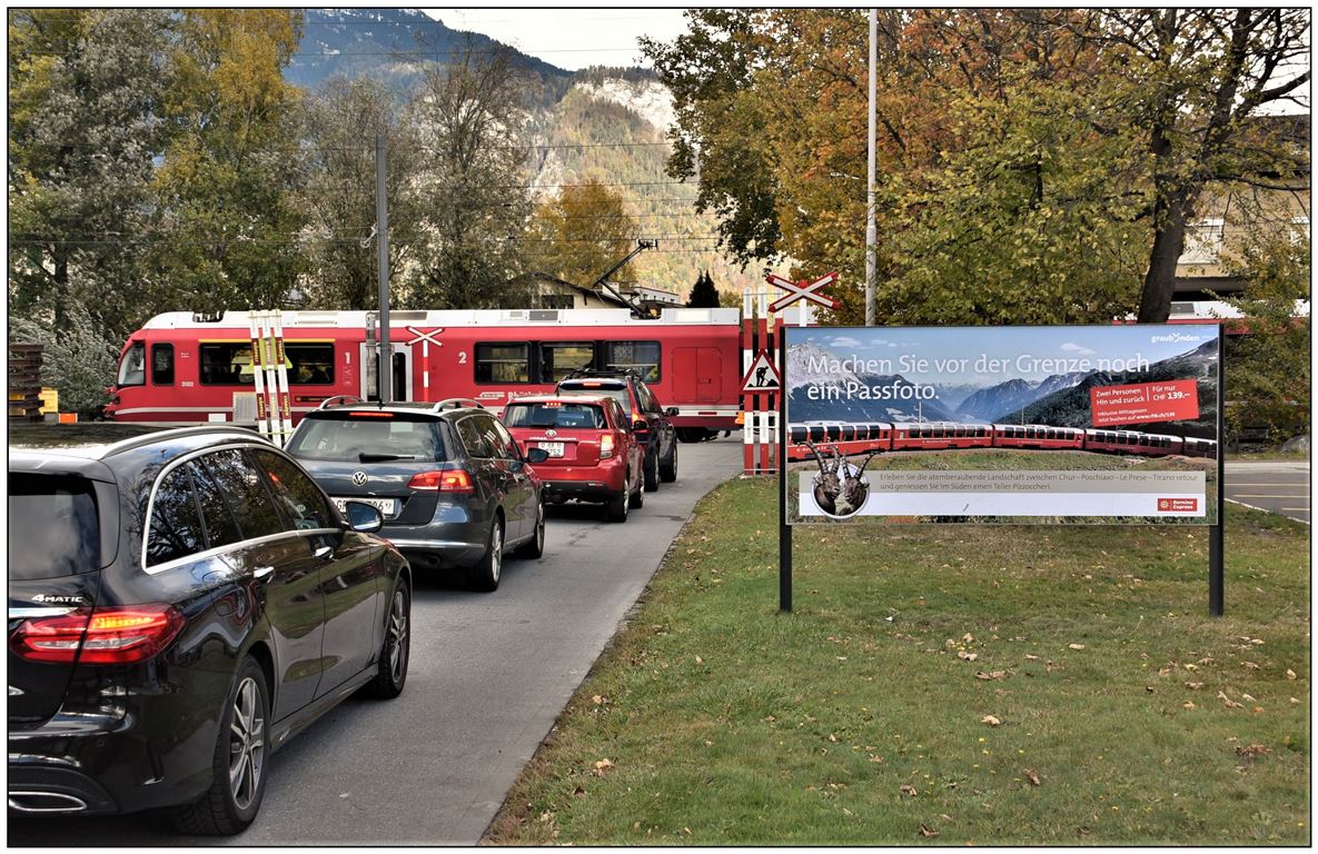 S1 1516mit ABe 4/16 3102 hat am Bahnübergang im Industriequartier von Landquart Ried eine ganze Autokolonne ausgebremst, Zeit genug für die Fahrer das Werbeplakat der RhB für eine Fahrt zu zweit im Berninaexpress zu studieren. (31.10.2018)