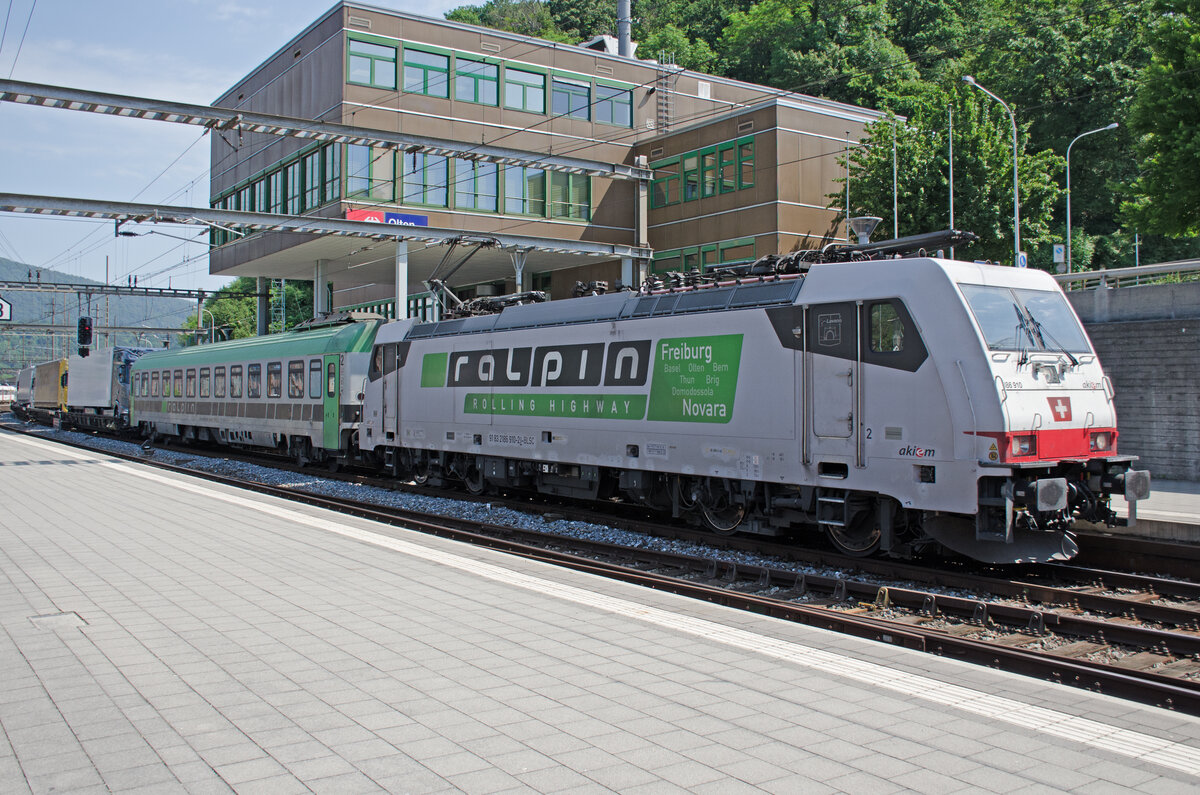 Samstag den 03.06.2023 um 11:19 Uhr in Olten. Auf Gleis 12 fährt soeben der RoLa-Zug 43615 (Pünktlich nach Fahrplan 11:19 Uhr) durch. RoLa bedeutet  Rollende Autobahn“: komplette Lastwagen werden an speziellen Terminals auf den Zug verladen und die Fahrer reisen in einem Begleitwagen mit. Dieser Zug verkehrt von Freiburg im Breisgau (D) über Basel – Olten - Bern – Thun – Brig – Domodossola nach Novara (I). Annahmeschluss in Freiburg war um 07:45 Uhr. Entladebereit in Novara ist er um 18:30 Uhr. Zuglok ist die 91 83 2186 910-2 I-BLSC (DB Baureihe 186 910) mit dem Wappen von Laveno. Lokhersteller: Bombardier. Typ: TRAXX F140 MS. Fabriknummer: 34371. Baujahr: 2008. Der Begleitwagen für die LKW-Fahrer ist ein Bcm 61 85 5900 ???-? CH-RALP. Dieser Wagen ist Klimatisiert. Koordinaten GMS (Grad, Minuten, Sekunden): N 47° 21’ 11.5’’ O 7° 54’ 30.3’’