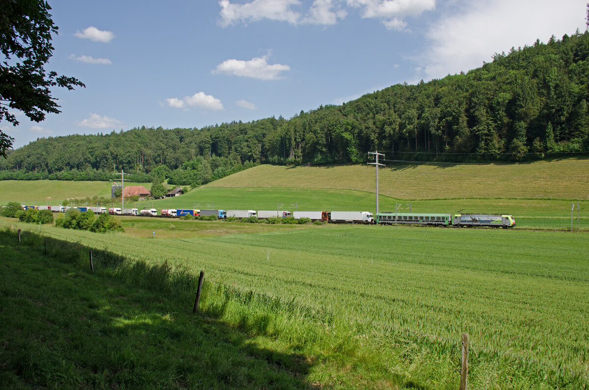 Samstag den 03.06.2023 um 16:38 Uhr in Wynigen. Auf der Höhe der Bickigematte fährt soeben der RoLa-Zug 43623 (mit einer Verspätung von 44 Minuten) durch. Fahrplanmässige Durchfahrt in Wynigen wäre um 15:54 Uhr. Grund der Verspätung ist das Umleiten des Zuges zwischen Basel und Olten. Statt direkt zu fahren, wurde dieser Zug über den Bözberg (Frick – Brugg – Othmarsingen – Lenzburg – Aarau) umgeleitet. Grund dafür sind Bauarbeiten auf der direkten Linie zwischen Basel und Olten. RoLa bedeutet  Rollende Autobahn“: komplette Lastwagen werden an speziellen Terminals auf den Zug verladen und die Fahrer reisen in einem Begleitwagen mit. Dieser Zug verkehrt von Freiburg im Breisgau (D) über Basel – Olten - Bern – Thun – Brig – Domodossola nach Novara (I). Annahmeschluss in Freiburg war um 11:15 Uhr (Pünktlich). Entladebereit in Novara wäre er um 22:30 Uhr. Ob der Zug die Verspätung noch Einholt wissen die Götter, aber nicht ich, da ich den Zug nicht weiterverfolgt habe. Zuglok ist die 91 85 4486 503-6 CH-BLSC (BLS Re 486 503). Lokhersteller: Bombardier. Typ: TRAXX F140 MS. Fabriknummer: 34404. Inbetriebnahme: 2009. Der Begleitwagen für die LKW-Fahrer ist der Bcm 61 85 5900 116-8 CH-RALP. Dieser Wagen ist Klimatisiert. Koordinaten GMS (Grad, Minuten, Sekunden): N 47° 5’ 48.3’’ O 7° 39’ 7.6’’