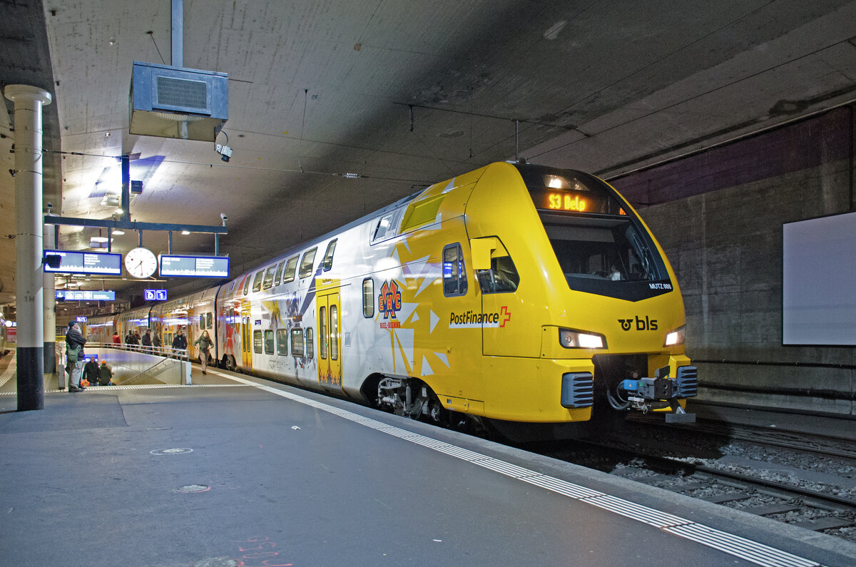 Samstag den 09.12.2023 um 07:29 Uhr in Bern. Im Bahnhof Bern auf Gleis 1 steht die S-Bahn 3 mit der Zugnummer 15324. Sie verkehrt von Biel/Bienne (Abfahrt um 06:54 Uhr) über Lyss – Zollikofen – Bern (Ankunft um 07:30 Uhr, Abfahrt um 07:32 Uhr) und weiter über Bern Weissenbühl – Kehrsatz nach Belp (Ankunft um 07:51 Uhr). Der Zug besteht aus dem BLS RABe 515 008 (Baureihe 515  MUTZ“). Es handelt sich hier um den neu lackierten Hockeyzug der BLS. Der Zug wirbt um die NLA Hockeyvereine im Einzugsbereich der BLS (SC Bern, EHC Biel, SC Langnau und HC Fribourg-Gottéron). Erbauer des Zuges ist Stadler Rail. Das Fahrzeug kommt aus der Fahrzeugfamilie  Stadler KISS“. Eingeweiht wurde der Zug mit der neuen Lackierung am 11.11.2023. Vor dieser Neulackierung hat der Zug für den SC Bern geworben. Der Zug besteht aus den folgenden Fahrzeugen (Spitze – Schluss wie auf dem Bild): 94 85 7515 108-9 CH-BLS, 94 85 7515 208-7 CH-BLS, 94 85 7515 408-3 CH-BLS, 94 85 7515 608-8 CH-BLS. Koordinaten GMS (Grad, Minuten, Sekunden): N 46° 56’ 54.8’’ O 7° 26’ 17.8’’