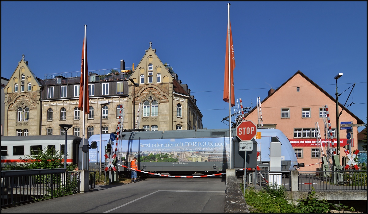 Sandwich mit zwei bunten Enden. 101 016-4 mit DER-Tours-Werbung für Wien am gestörten Bahnübergang vor dem Inselhotel Konstanz. Juni 2014.