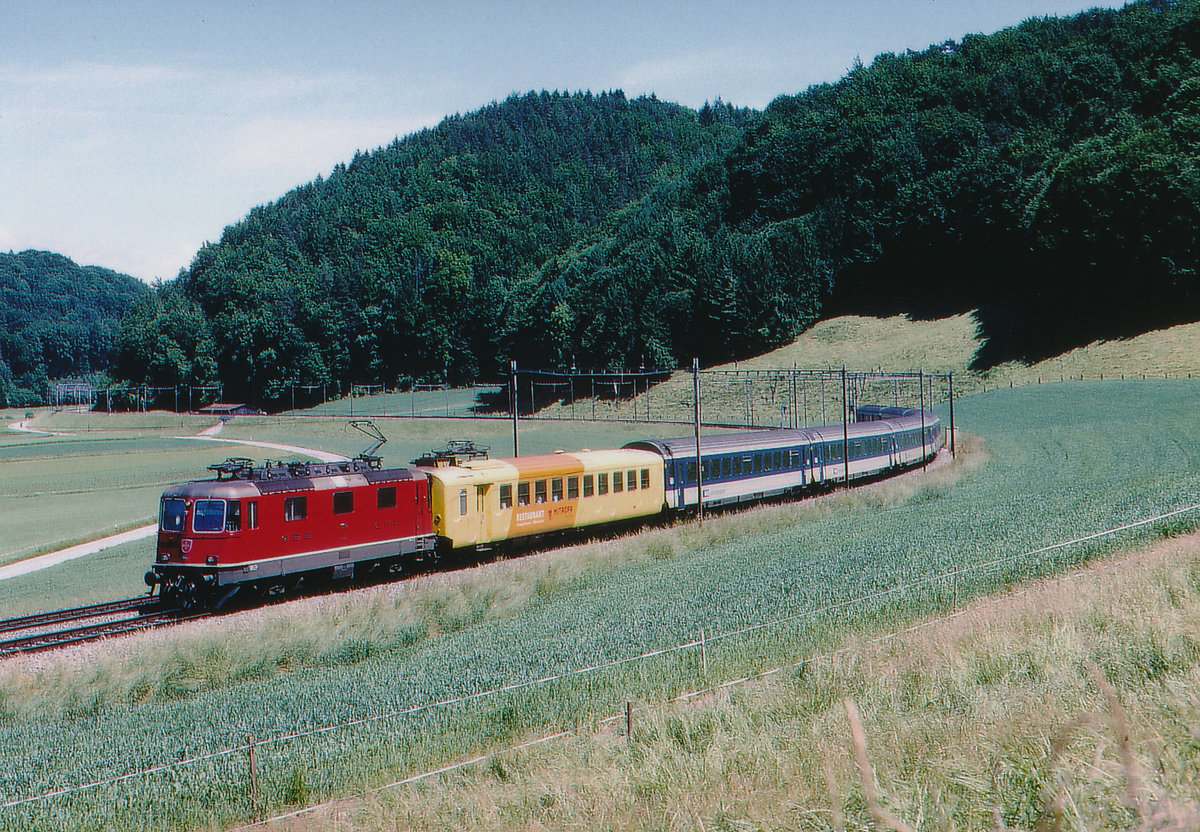 SBB:  CHÄS EXPRESS 
Re 4/4 mit Intercity Basel-Brig bei Wynigen im Juli 1999. Besondere Beachtung gilt den blauen EW IV der BLS sowie dem MITROPA KÄSEWAGEN der dritten Ausführung, eingereiht hinter der Lok.
Foto: Walter Ruetsch