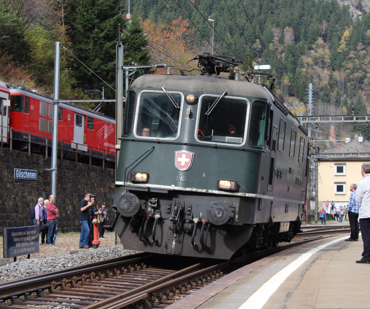 SBB Re 4/4 II Nr. 11164 wird auf Gleis 1 im Bahnhof Göschenen noch wenige Meter in den Gotthard(-scheitel-)tunnel hineinfahren. Im Bild sieht man auch einen gerade abfahrenden Regio von Göschenen nach Andermatt. Am Zugsende des R sieht man der MGB Gepäcktriebwagen Deh 4/4 I Nr. 52  Tujetsch/Sedrun 
