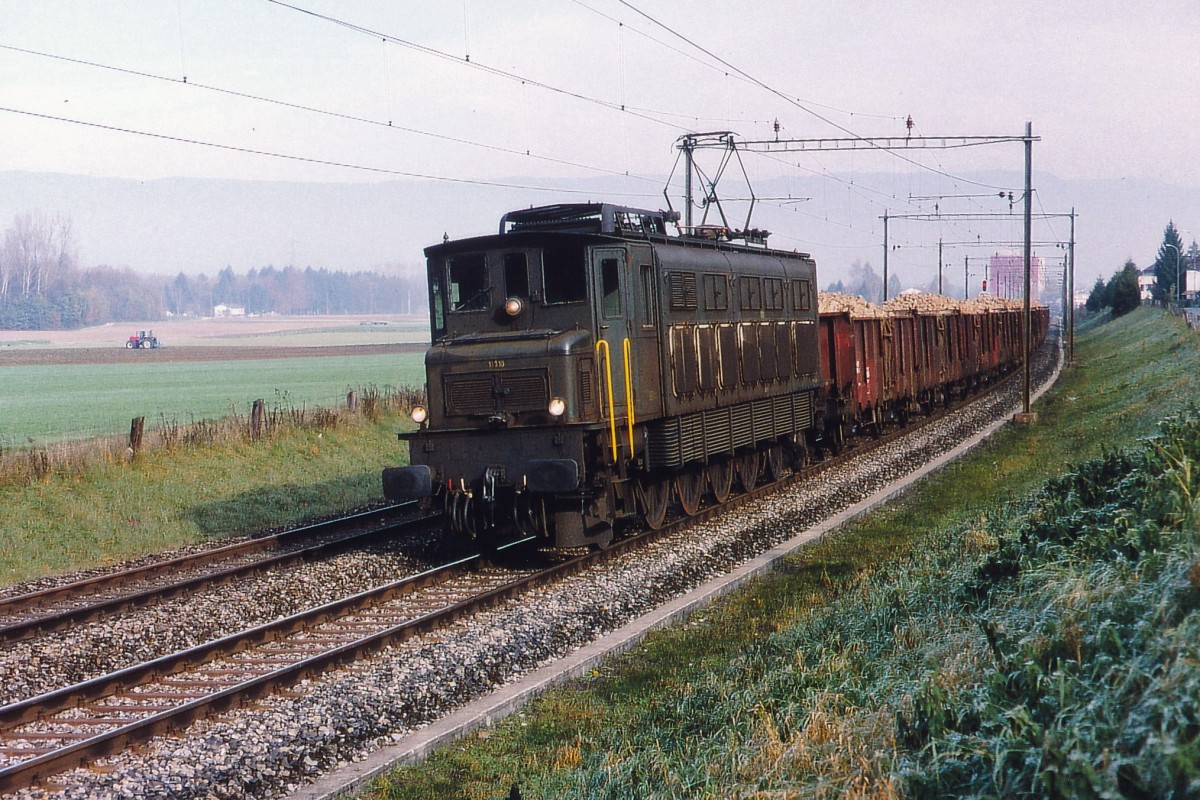 SBB: Seit dem 21. September  ist die Zuckerrübenkampagne 2015 voll im Gang. In den Zuckerrübenfabriken Aarberg und Frauenfeld wird wieder rund um die Uhr gearbeitet und am Tag und  l e i d e r  meist bei Nacht verkehren die langen Zuckerrübenzüge von SBB CARGO mit Re 420. Die Zuckerrüben, die von der Bahn nicht mehr transportiert werden, bringen die Landwirte mit ihren Fuhrwerken direkt nach Aarberg, was den bereits stark belasteten Strassenverkehr während den nächsten 3 Monaten zusätzlich behindert. Im Oktober 1995 wurden die Zuckerrüben aus der Region Büren an der Aare noch mit einer Ae 4/7 und zweiachsigen Güterwagen nach Aarberg geschleppt. Die Aufnahme, die an einem trüben und nebligen Morgen bei Busswil bei Büren entstanden ist, erinnert mich noch immer an den bekannten Bahnfotografen und Buchautor Hans Schneeberger. Kurze Zeit nachdem wir beide gemeinsam diesen Rübenzug verewigt hatten, ist er nämlich nur wenige Kilometer von dieser Fotostelle entfernt bei einem Autounfall in Lyss tödlich verunfallt. 
Foto: Walter Ruetsch
