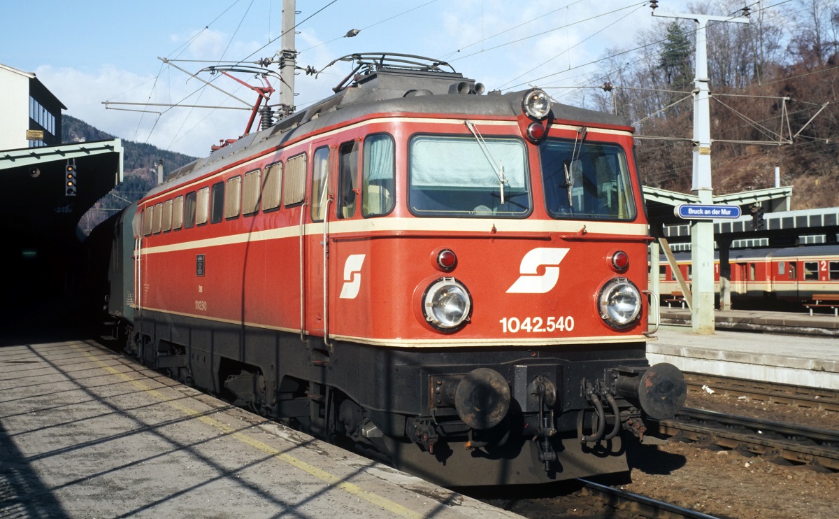 Scan vom Dia: Die im Bhf. Bruck an der Mur wartende 1042.540 war die letzte Lok, die 1969 unter der Fabr. Nr. 18381 im SGP - Werk Wien - Floridsdorf (vormals Lofag) gebaut wurde. Alle weiteren Maschinen dieser Reihe (1042.541 - 707) entstanden im SGP - Werk Graz, das viele Jahre später von Siemens übernommen wurde und heute als Kompetenzzentrum im Drehgestellbau gilt. (27.12.1983)