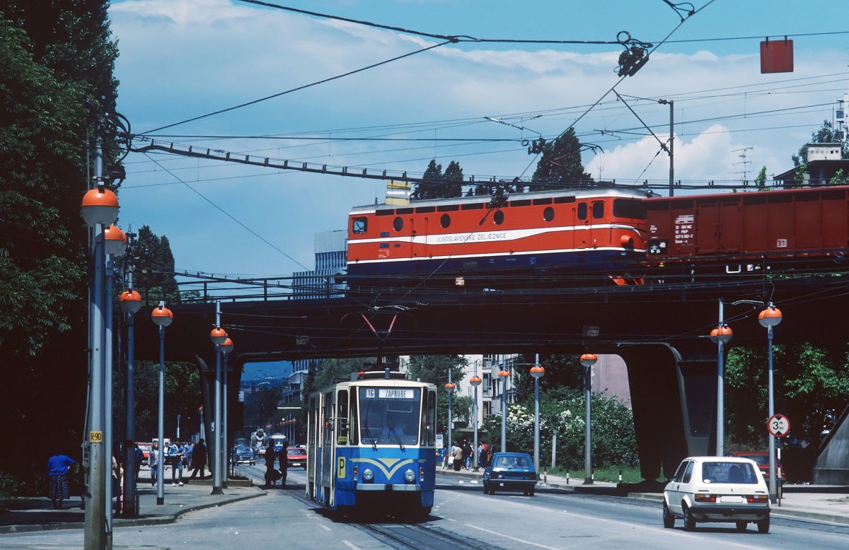 Scan vom Dia: Ein leider unbekannt gebliebener Triebwagen der Linie 16 vom Typ KT4YU macht sich in der Savska cesta auf den Weg nach Zaprude, während ein von einer JZ 441 gezogener Güterzug die Szene im Hintergrund überquert. (08.05.1986)