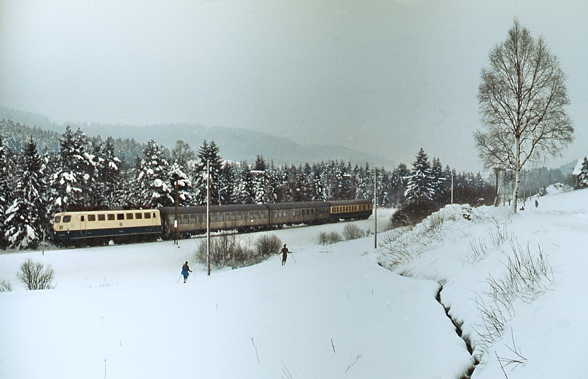 Schon einige Zeit liegt der Einsatz der Baureihe 139 auf der Höllentalbahn zurück. Im  Februar 1982 ist eine unbekannte 139 zwischen Titisee und Hinterzarten ungefähr an der gleichen Stelle wie auf den beiden vorhergehenden Aufnahmen unterwegs. Nicht nur beim Fotografen, sondern auch bei den beiden Langläufern stößt der Zug auf Interesse.