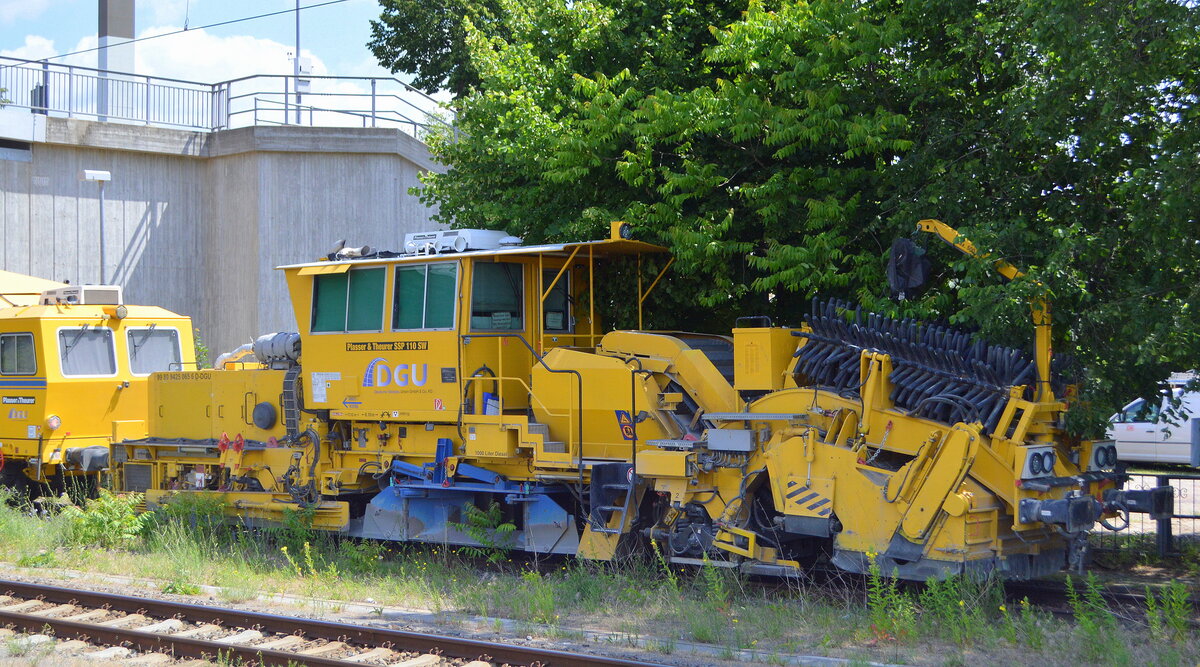 Schotterplanier- und Profilierungsmaschine P &T Typ SSP 110 SW der DGU - Deutsche Gleisbau Union GmbH & Co.KG ( 99 80 9425 065-6 D-DGU ) neben einer DGU Gleisstopfmaschine am 10.06.22 Dessau Hbf abgestellt.