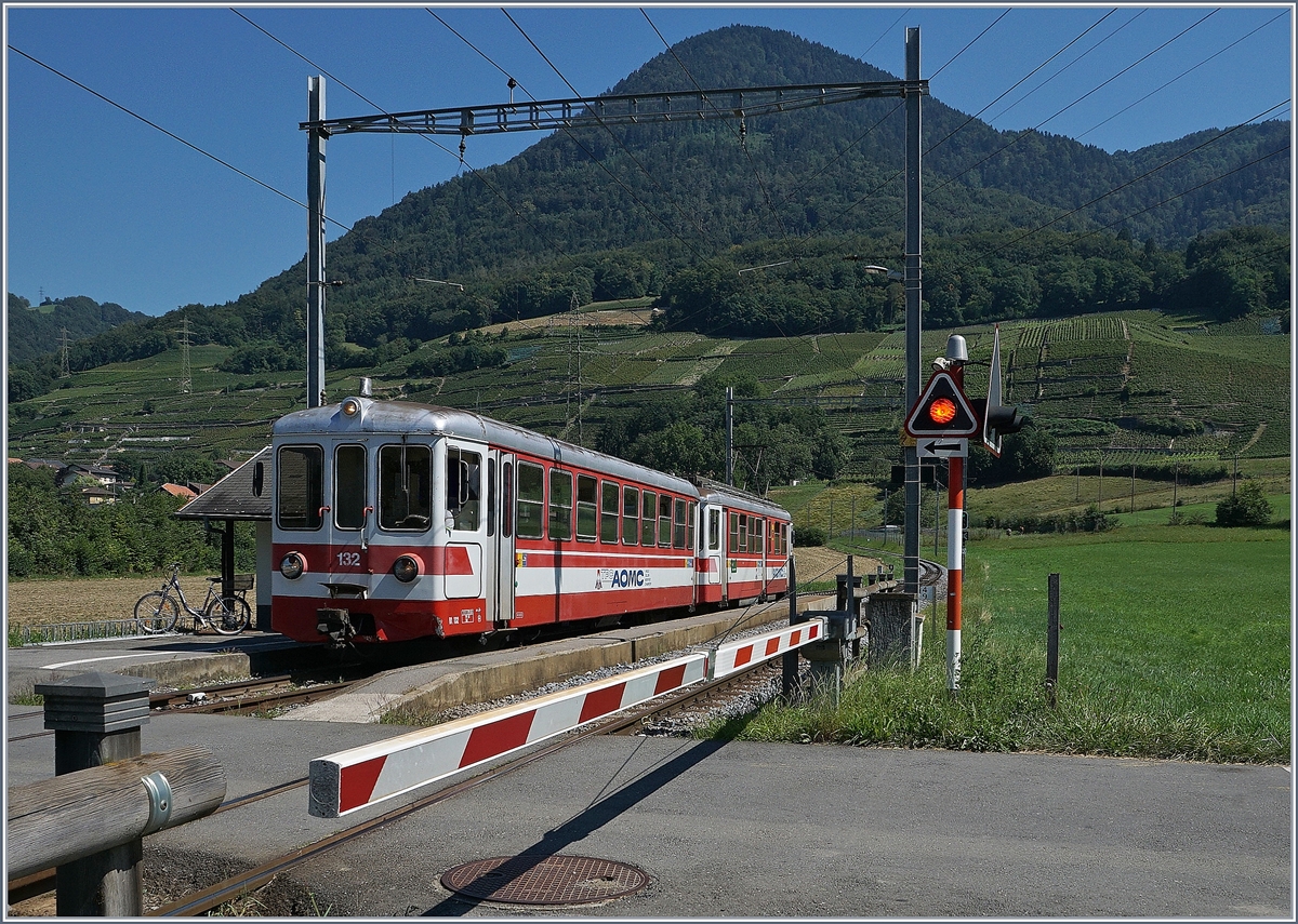 Schranken,  wenn sich Bahn und Strasse kreuzen: In Villy wartet der AOMC Bt 132 und ein schiebender Be 4/4 (beide ex Birsigtalbahn) auf die Abfahrt Richtung Monthey-Ville.
26. August 2016