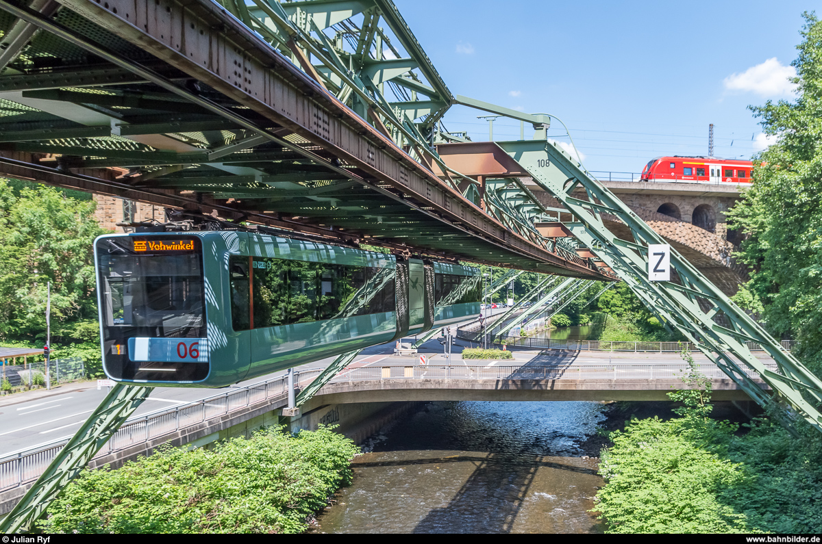 Schwebebahn Wuppertal: Wagen 06 erreicht am 5. Juni 2017 die Haltestelle Zoo/Stadion, während die Eisenbahnbrücke gerade von einer Grinsekatze (BR 440) der DB befahren wird.