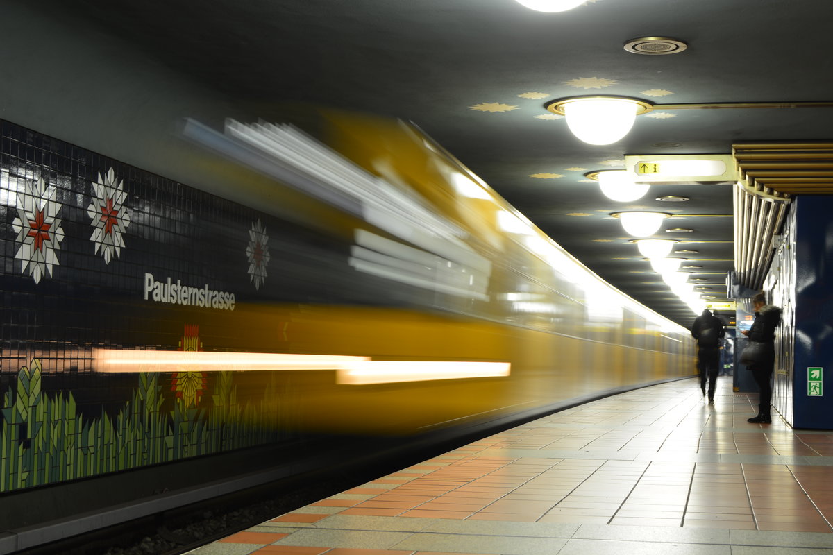 Sehr bunt ist die am 1. Oktober 1984 eröffnete U-bahn Station Paulsternstraße. Sie wurde in Zuge der Verlängerung nach Spandau Rathaus eröffnet. Der U-Bahnhof Paulsternstraße wurde, wie die meisten Berliner U-Bahn-Nachkriegs-Neubauten, vom Architekten Rainer G. Rümmler entworfen. Da Rümmler zur Zeit des Entwurfes an der Oberfläche keine Anreize für eine Gestaltung des U-Bahnhofs fand, orientierte er sich bei seinem Entwurf an der Geschichte des Ortes. Hier fand er das Große Rohrbruch, ein Niederungsgebiet am ehemaligen Verlauf der Spree, einen Kiefernwald, der sich einst von hier bis zur Jungfernheide erstreckte, und die historische Gemarkungsbezeichnung Sternfelde. Hieraus filterte er Begriffe wie Stern, Luchlandschaft, Wald, Bäume und einsamer Falter. Diese wiederum setzte er in Architektur um. So wurden die Mittelstützen des Bahnhofs zu Bäumen und die Sockel der Wände mit Schilf und Gras zu einer Luchlandschaft. An einen dunklen Himmel setzte Rümmler Sterne und einen „kalten Mond“, die einen Nachtfalter bescheinen. Der Bahnhof Paulsternstraße gilt, im Vergleich mit anderen Bahnhöfen, aber auch auf der 1980 und 1984 eröffneten Strecke Richard-Wagner-Platz – Rathaus Spandau als hervorstechendes Beispiel der Rümmlerschen Architektur. Der U-Bahn-Kritiker Jan Gympel moniert beim Bahnhof Paulsternstraße besonders die „entgegenspringenden Kapitelle […] auf knubbeligen Stützverkleidungen“. Allgemein hält Gympel den Bahnhof für zu bunt, zu prunkvoll und übersät mit „kruden Mustern“. Hier rauscht eine U7 in den U-Bahnhof. 

Berlin Paulsternstraße 03.01.2018


Seite „U-Bahnhof Paulsternstraße“. In: Wikipedia, Die freie Enzyklopädie. Bearbeitungsstand: 23. Juli 2017, 16:32 UTC. URL: https://de.wikipedia.org/w/index.php?title=U-Bahnhof_Paulsternstra%C3%9Fe&oldid=167520946