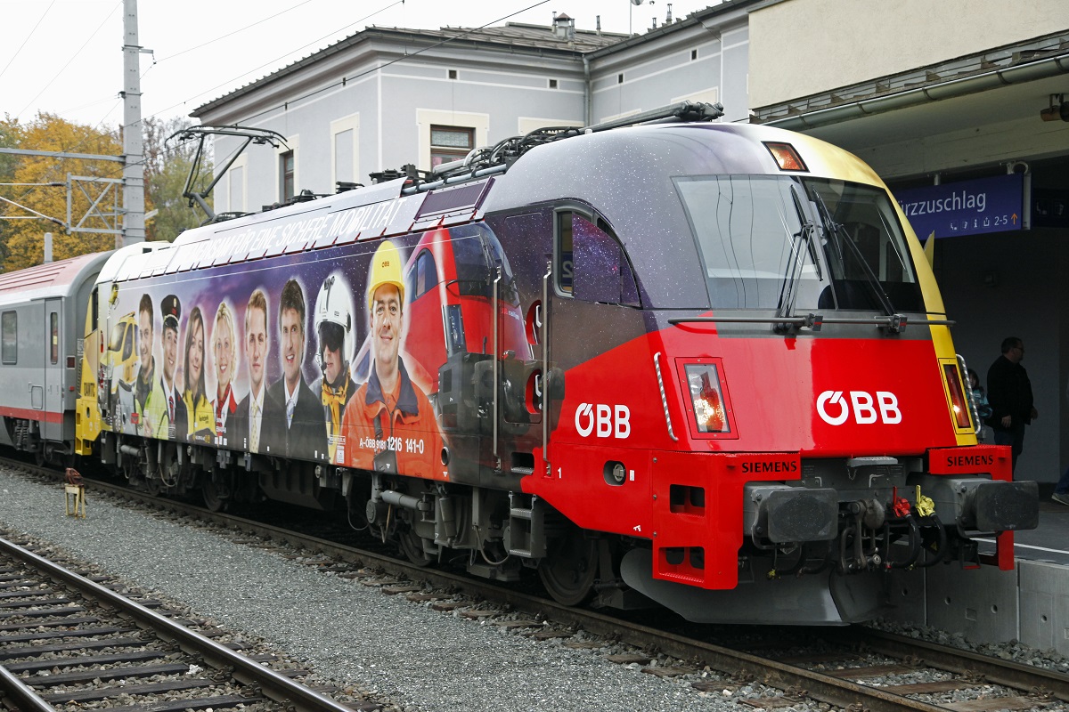 Seit 14.10.2013 besitzen die �BB eine neue Werbelok. Gemeinsam werben auf der 1216.141 die �BB und der �AMTC f�r eine sichere Mobilit�t. Das Bild zeigt die Lok bei ihrer ersten Ausfahrt mit EC159 beim Zwischenhalt in M�rzzuschlag am 14.10.2013.