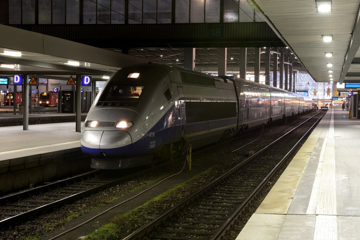 Seit 2007 ein täglicher Gast im Münchner Hauptbahnhof ist der TGV. Aufnahmen gibt es allerdings nur wenige vom französischen Hochgeschwindigkeitszug in der bayerischen Landeshauptstadt. Dies ist dem Umstand geschuldet, dass die Verbindung von und nach Paris in Tagesrandlage erfolgt. Vor wenigen Minuten ist TGV 9575 aus Paris Est auf Gleis 18 eingefahren. Der Tf hat den Führerstand gewechselt und bringt den TGV POS 4719 nun in die Nachtabstellung in die VS. Links im Bild geht es provinzieller zu. Zwei ET 440 mit Fahrzielen in Niederbayern sind zu erkennen (25. Dezember 2013).
