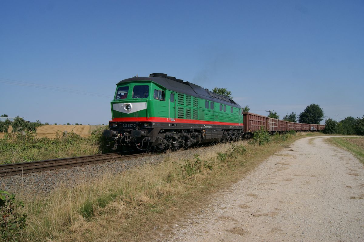 Seit 2014 ist die Wismut-Werkbahn unter Verantwortung der Starkenberger Baustoffwerke, die weitere Ludmillas beschafft hat, um externe Kunden zu beliefern. Ein solcher Zug ist hier am 19.08.2016 mit 241 697 bei Großbraunshain unterwegs.