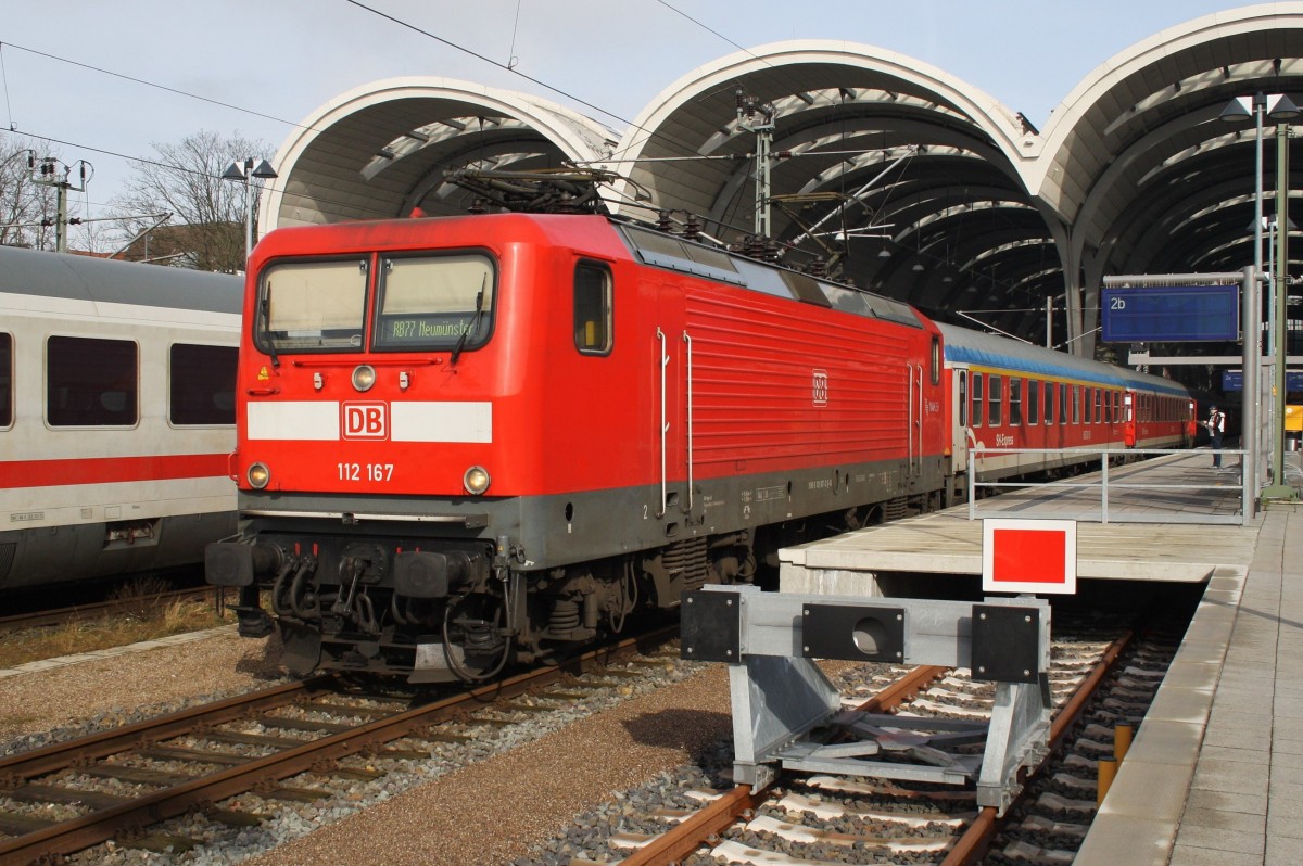 Seit dem 27.2.2016 verkehrt die Regionalbahn 77 von Kiel nach Neumünster vom Gleis 2a des Kieler Hauptbahnhofs. Wie auf dem Bild zuerkennen ist dieser Bahnsteig für die 112 mit ihren 5 Wagen minimal zukurz, so dass die 112 teilweise über diesen hinausragt. Hier ist es 112 167, die mit einer RB77 (RB21119) von Kiel nach Neumünster auf ihre Abfahrt wartet. 