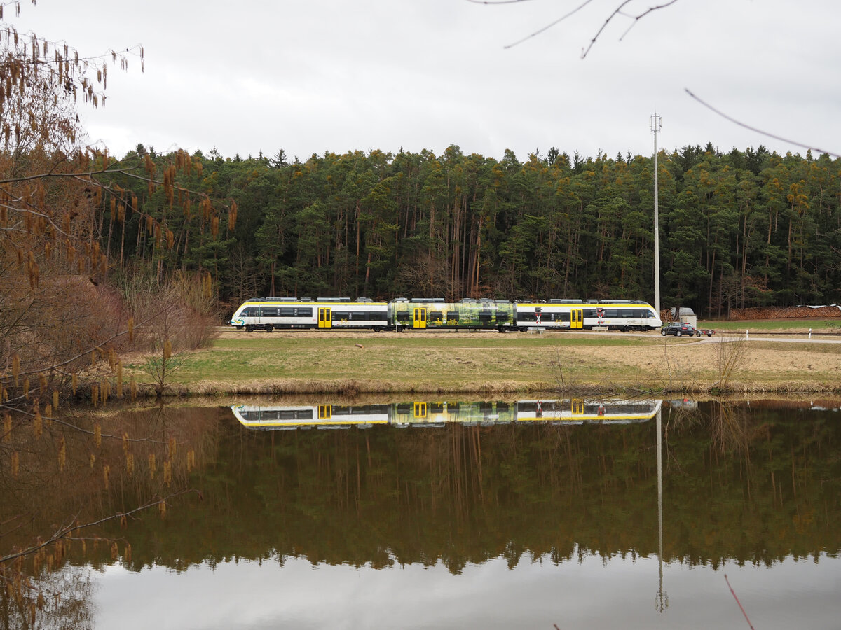 Seit dem 5.2.22 fährt am Wochenende zwischen Gunzenhausen und Pleinfeld auf der Seenlandbahn der BEMU von Alstom (ex Bomardier, siehe auch Fahrzeuganschriften).

Hier passiert der Zug einen Weiher nahe Langlau.
Langlau, der 26.02.2022