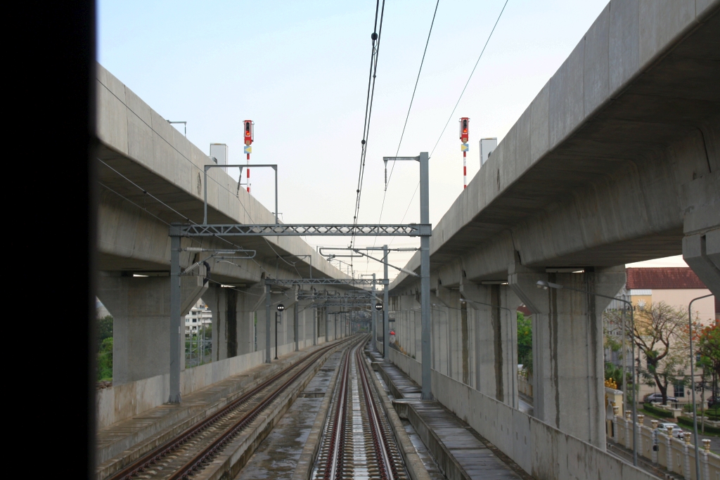 Seit der Inbetriebnahme der Krungthep Aphiwat Station der SRT (vorher Bang Sue Grand Station genannt) am 19.Jänner 2023 fahren alle SP.EXP, EXP und RAP der Northern und North Eastern Line von dort ab und mit Halt nur in Don Muang Station bis kurz vor Rangsit in Hochlage. Die ORD, LOC und COM fahren nach wie vor von der Hua Lamphong Station ab und wechseln dann nach der Nikhom Rotfai Km. 11 Station in die Hochlagetrasse. - Das Bild vom 28.April 2023 (aufgenommen durch die Stirnwandtüre des letzten Wagen des ORD 207) zeigt die Rampe zur Hochlage nach der Nikhom Rotfai Km. 11 Station. Rechts und links erkennt man die Hochlage-Trasse von der Krungthep Aphiwat Station kommend.
