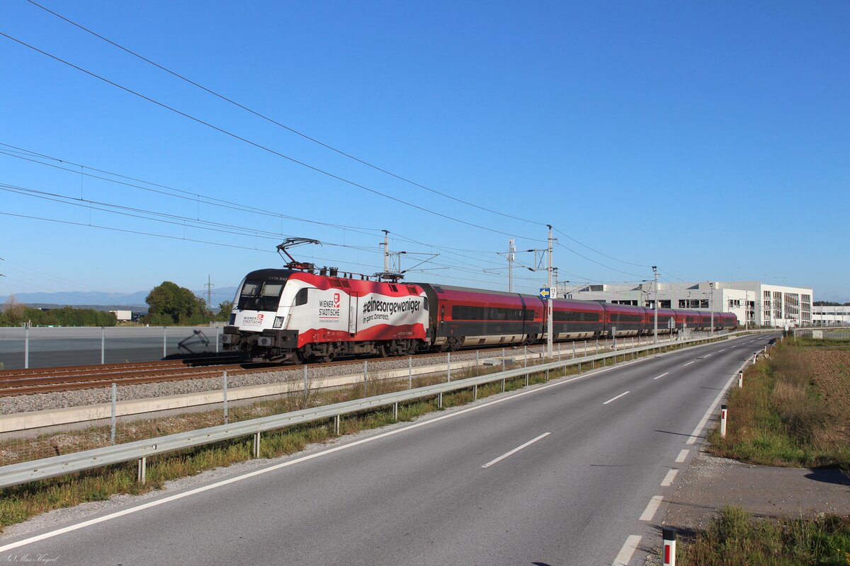 Seit Mai 2025 wirbt die 1116 247 f�r die Versicherungsgesellschaft  Wiener St�dtische  in Form einer �sterreich Flagge mit Werbespruch.
Am 23.9.2026 schiebt sie den RJ857  Weissensee  von Lienz in Osttirol nach Wien Hbf.
Der Zug wird hier gleich im 3251m langen Flughafentunnel verschwinden, der unter dem Flughafen Graz hindurch Richtung Graz Puntigam f�hrt.
