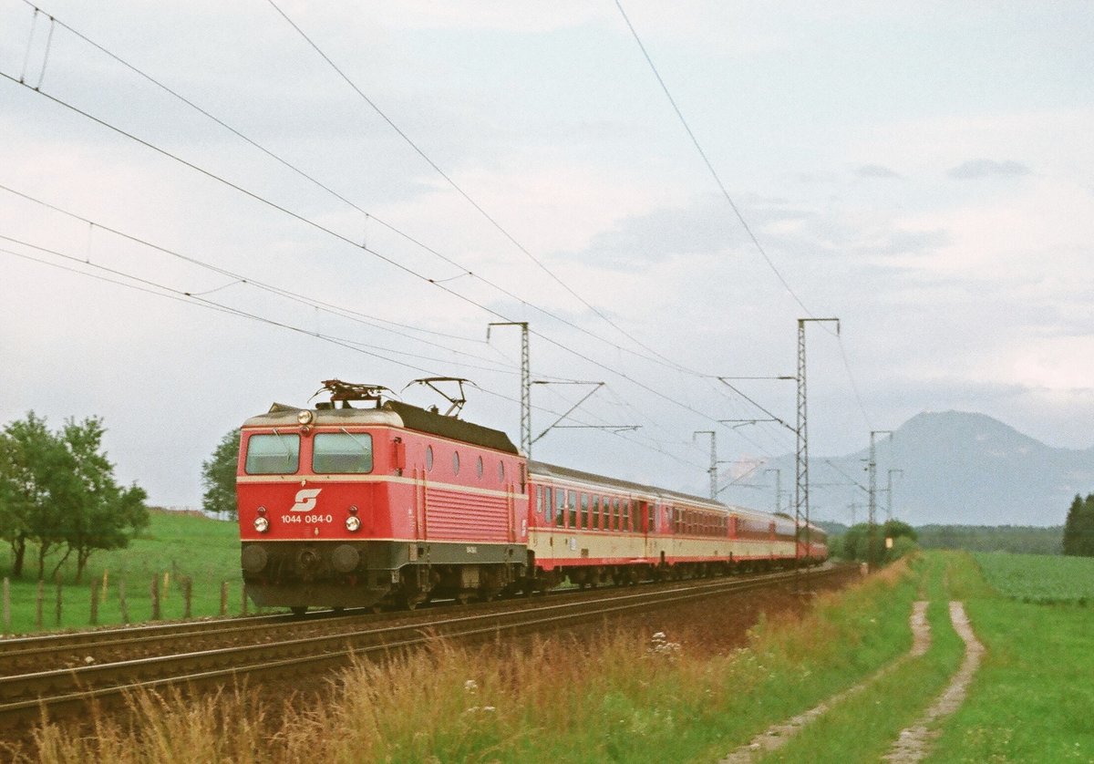 September 1988:	Bei Freilassing fährt ein Zug der ÖBB mit Lok 1044 084-0 in Richtung Rosenheim.
