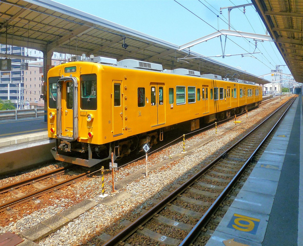 Serie 105 (3-türig): Heute sind die Züge Serie 105 im Raum Hiroshima in leuchtendem Gelb gestrichen. Im Bild steht die Komposition KUHA 104-26 und KUMOHA 105-31 in Fukuyama, etwas östlich von Hiroshima, bereit zur Fahrt durch die Vororte bis an die Berge heran; ab da geht es dann mit Diesel-Schienenbus weiter. 13.August 2013. 