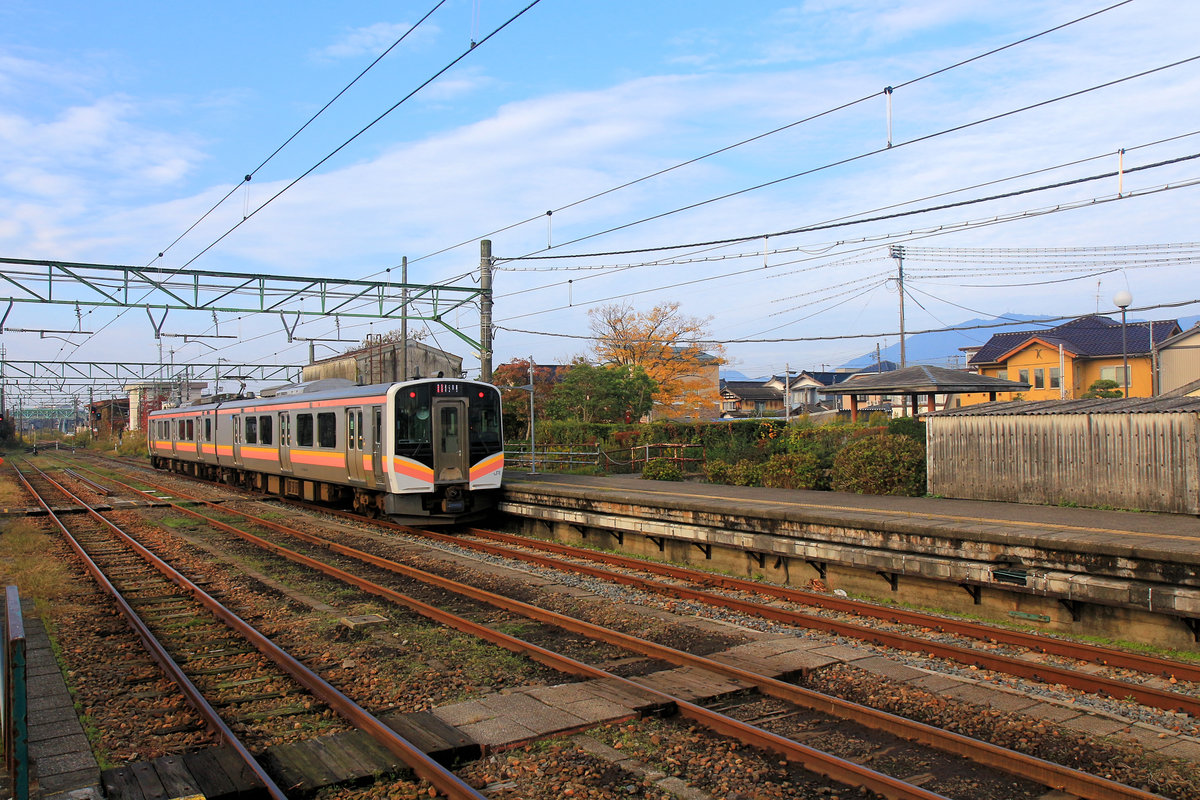 Serie 129, die neuen Triebzüge für die Präfektur Niigata (Japan, am Japanischen Meer). Ausfahrt von Zug 129-114 in Richtung des im Hintergrund sichtbaren heiligen Berges Yahiko. Yoshida, 12.November 2018 
